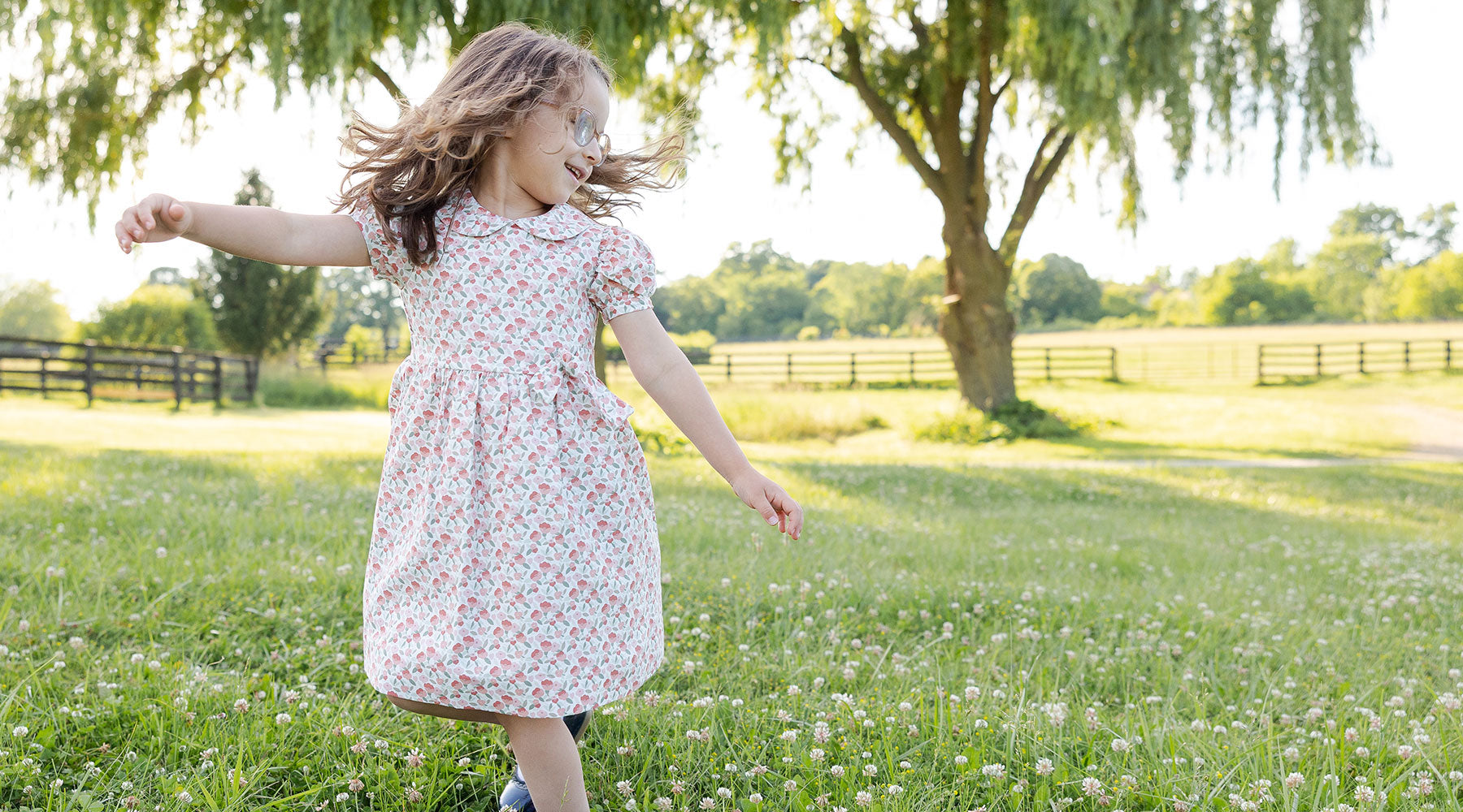 little girl dancing in a field in a floral dress