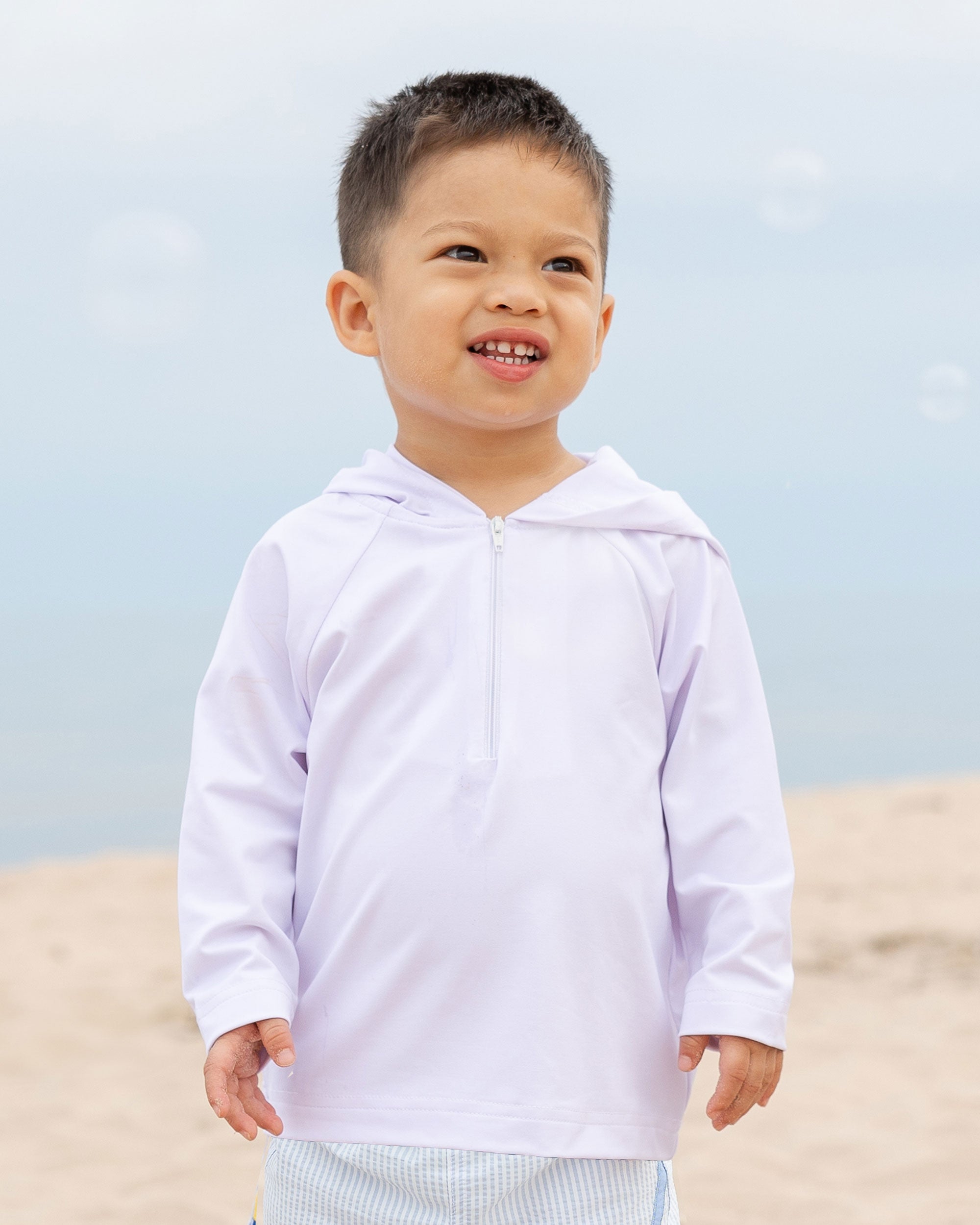 young boy on beach in white hooded rashguard