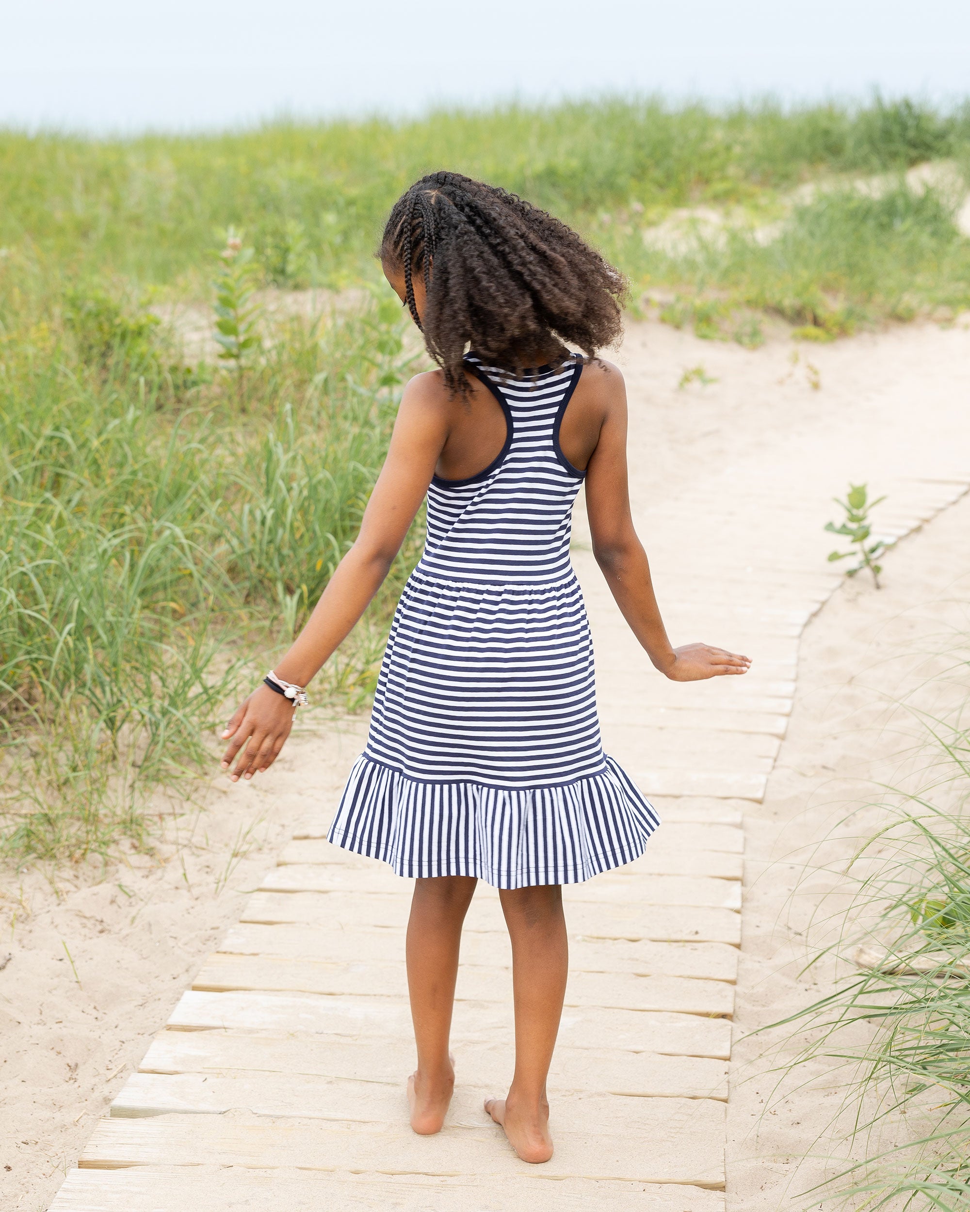 back view of girl in navy stripe dress on beach