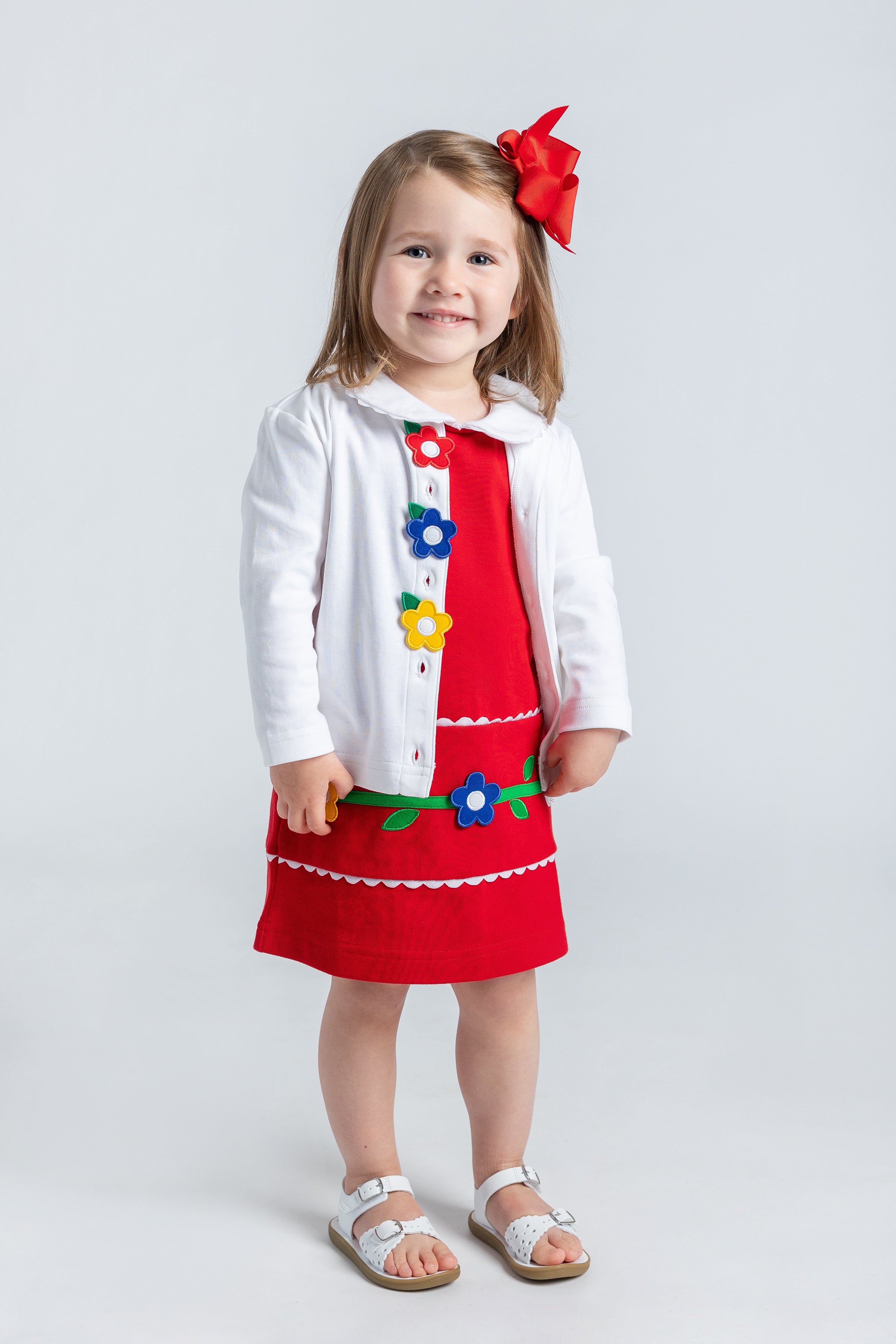 young girl wearing a cardigan and red dress