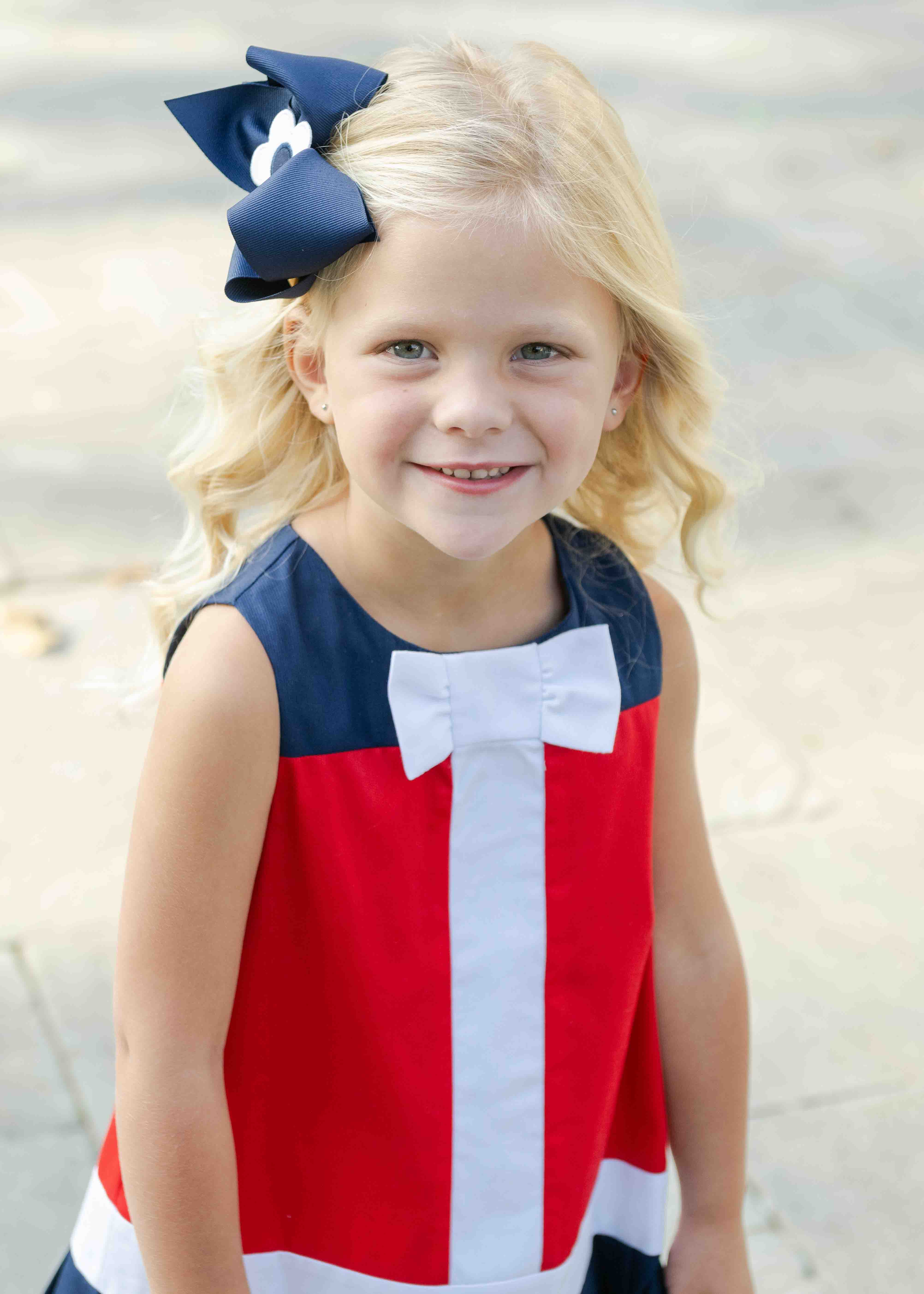 closeup of young girl in red and navy dress with white bow