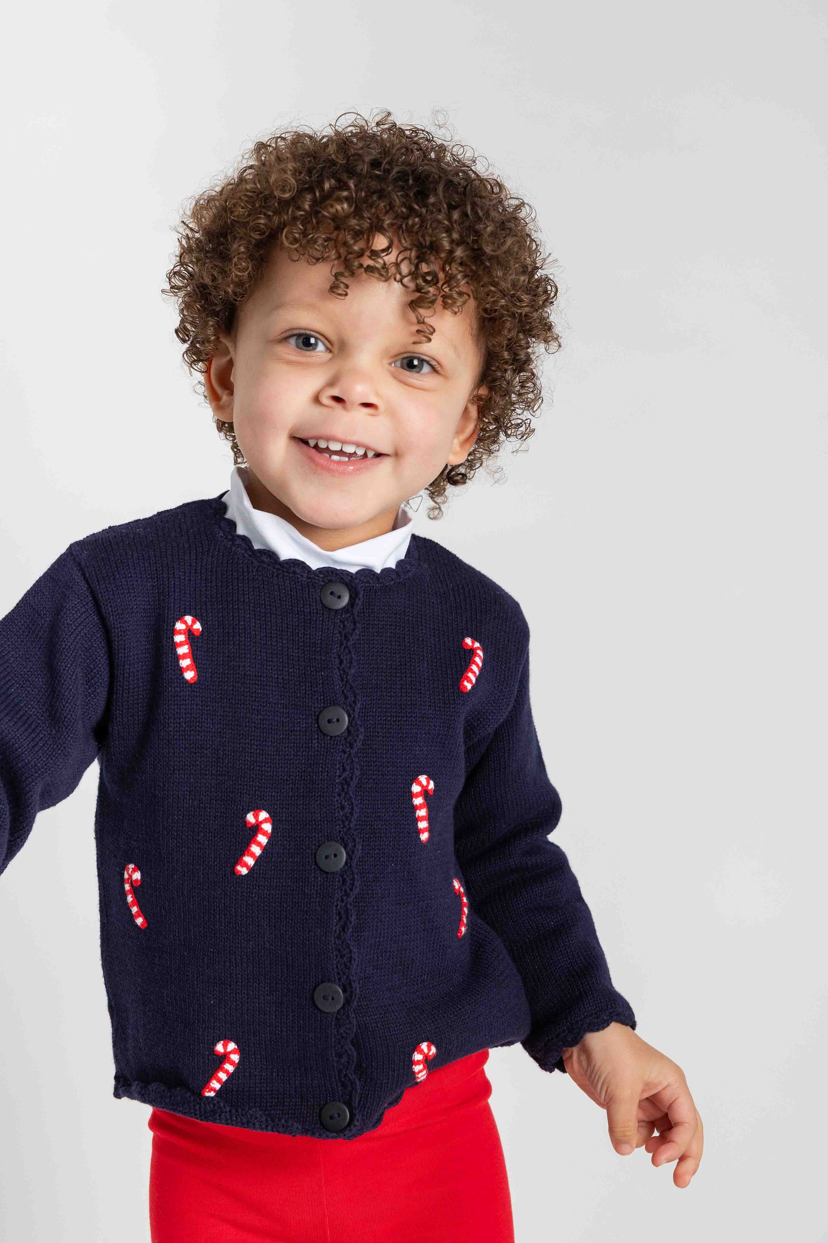 Child wearing a navy sweater with candy cane patterns on a white background