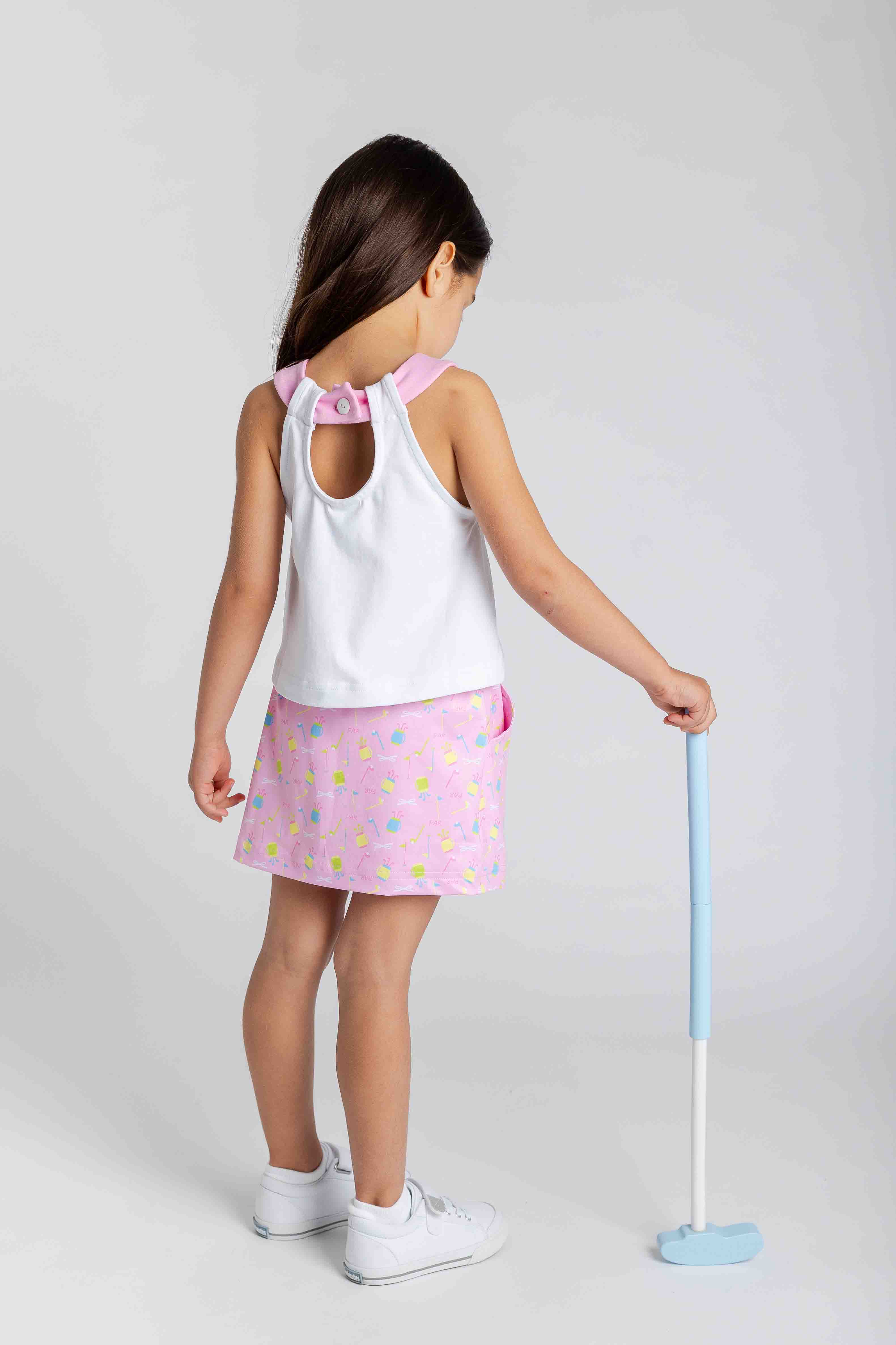 Child wearing a white top and pink golf themed skirt, holding a blue toy golf club on a light gray background.