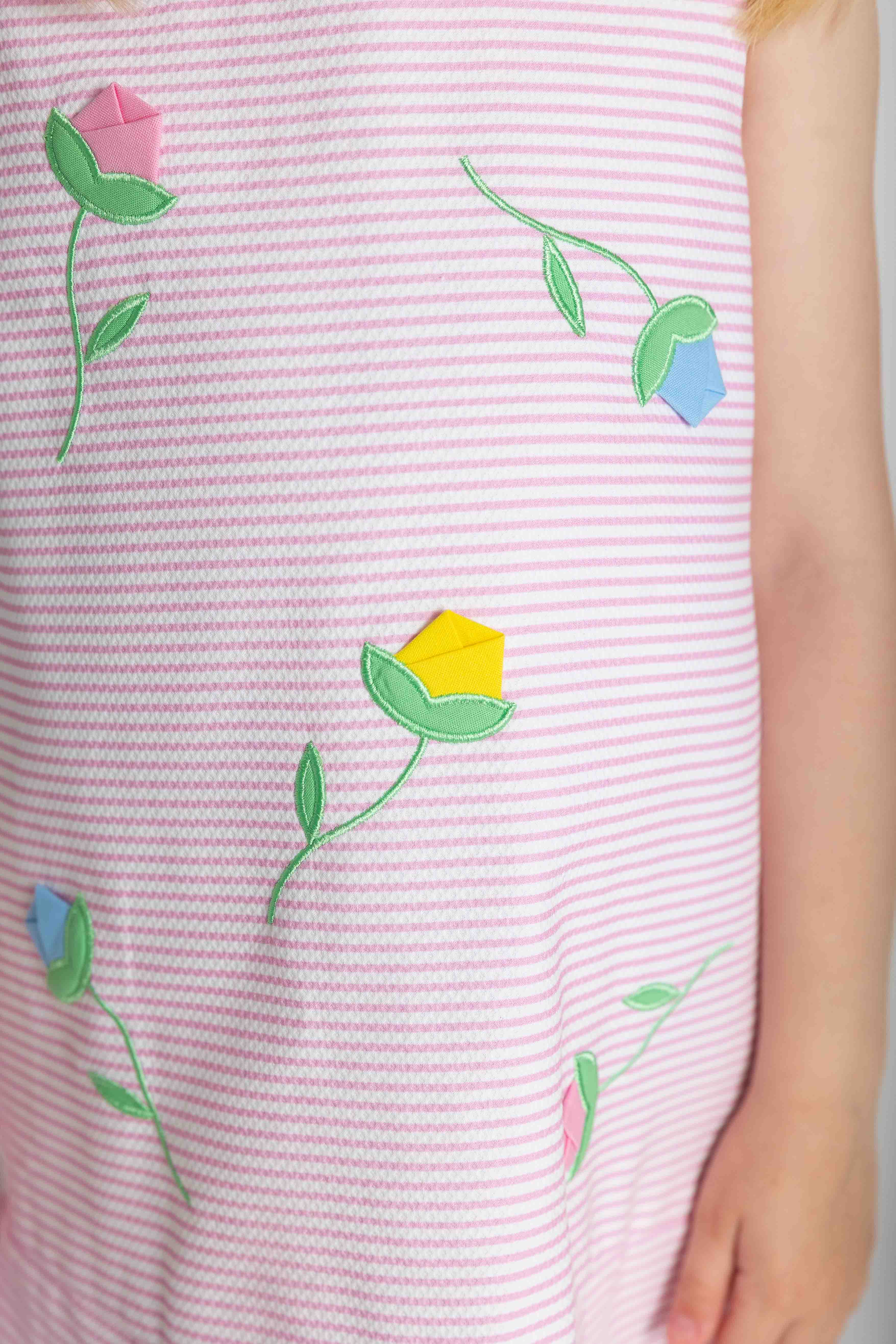 Pink striped fabric with embroidered flowers on a plain background
