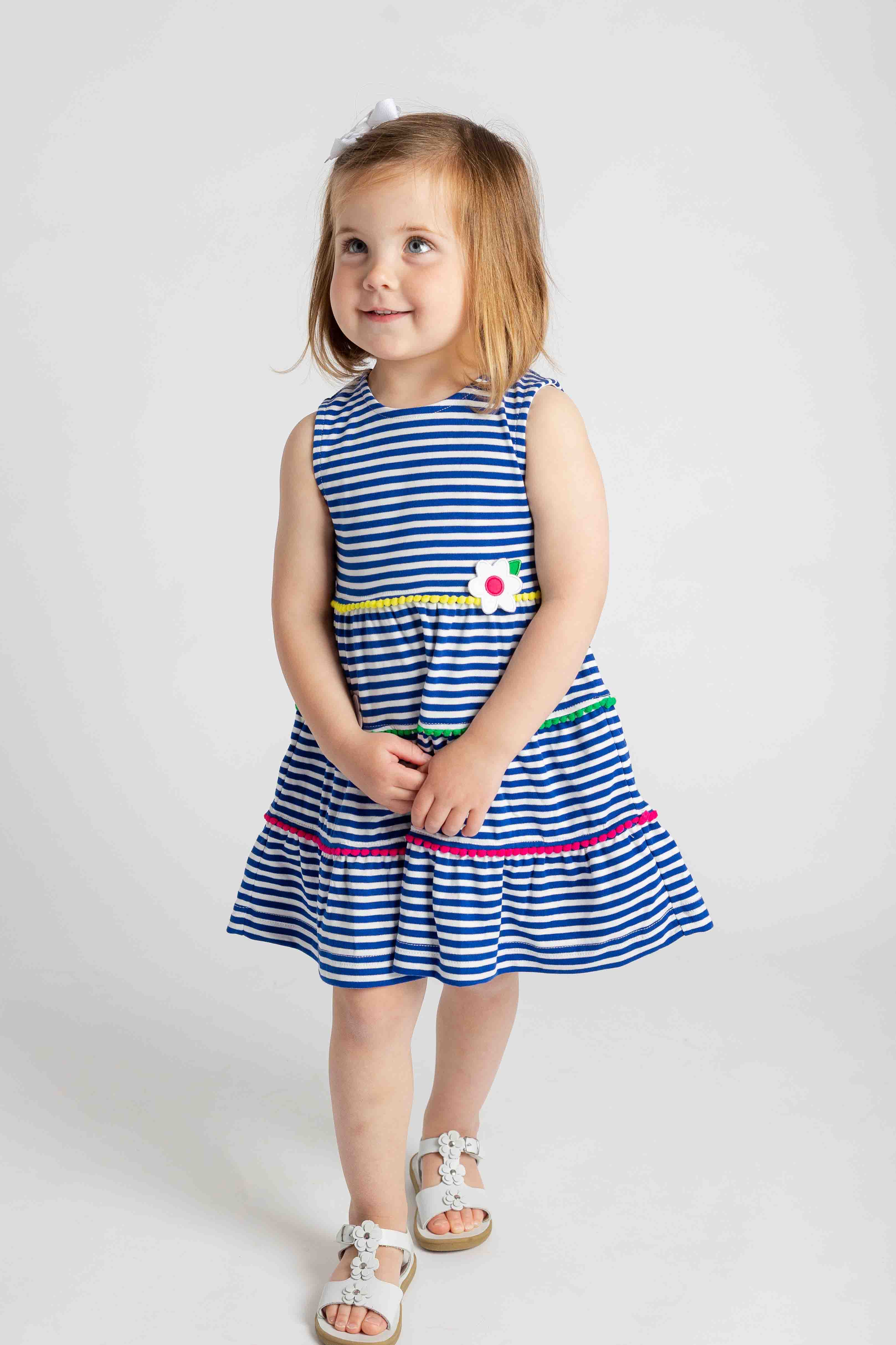 Young girl wearing a blue and white striped dress with colorful accents on a white background
