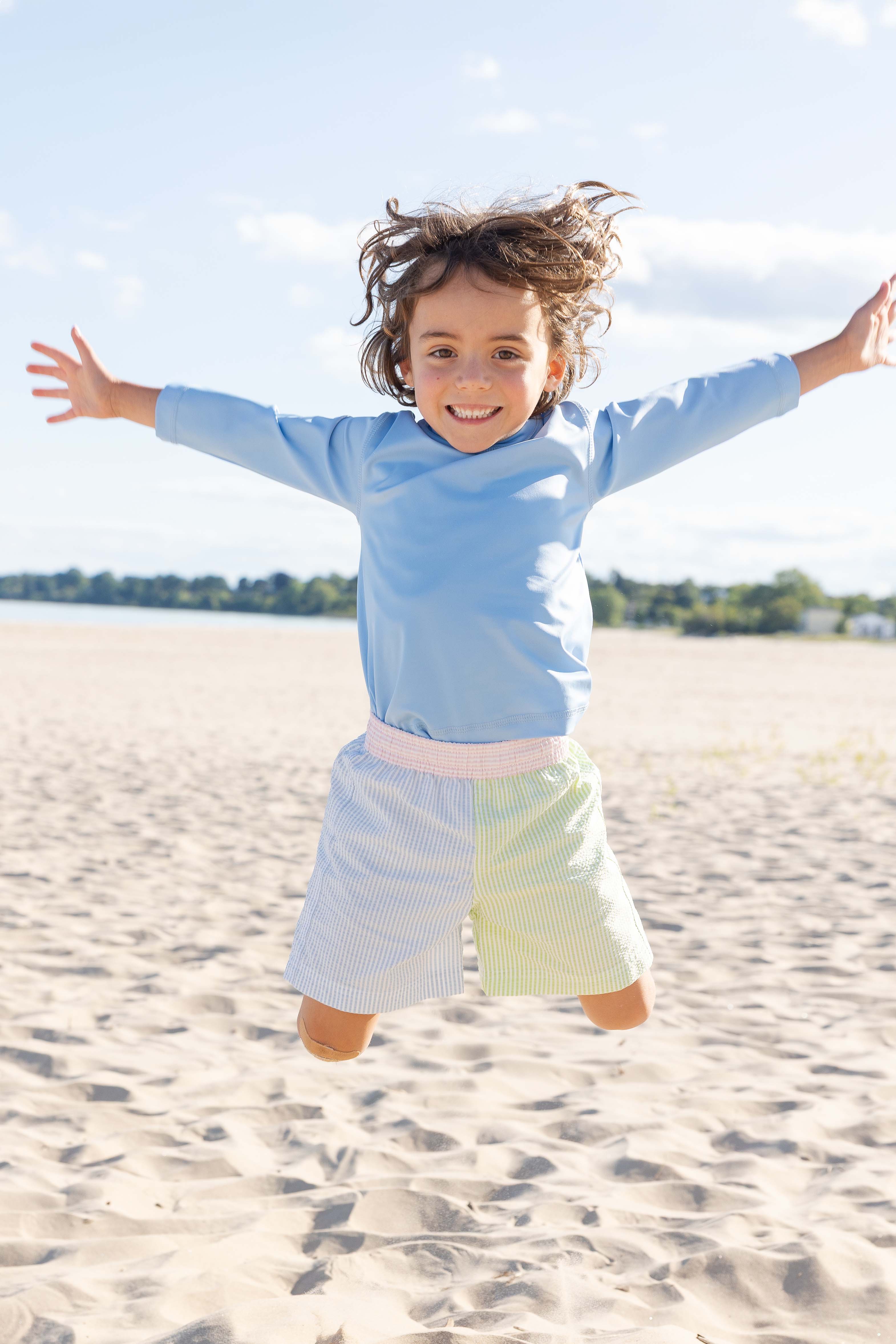 Child jumping on a sandy beach with arms outstretched