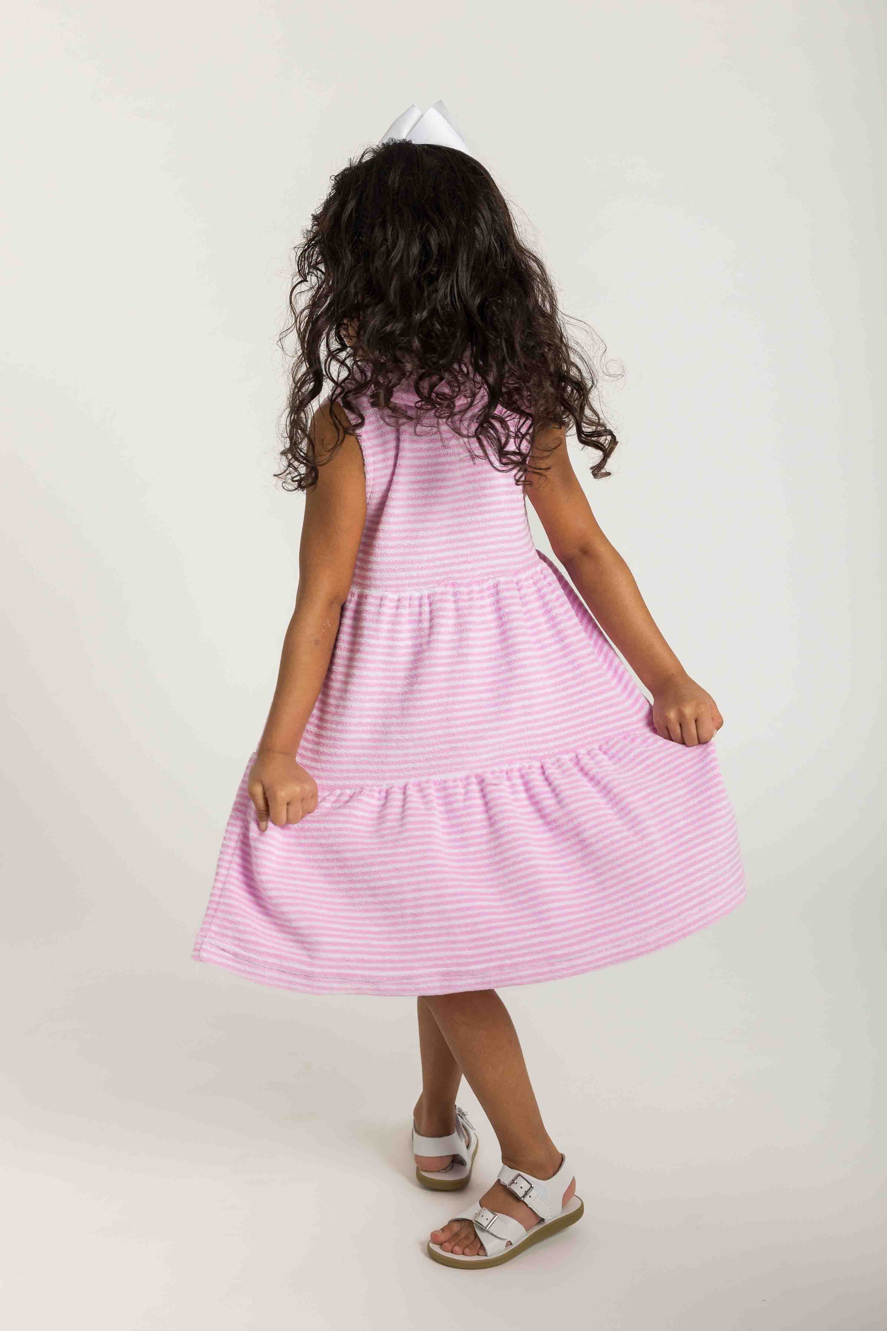 Young girl wearing a pink striped dress on a plain background