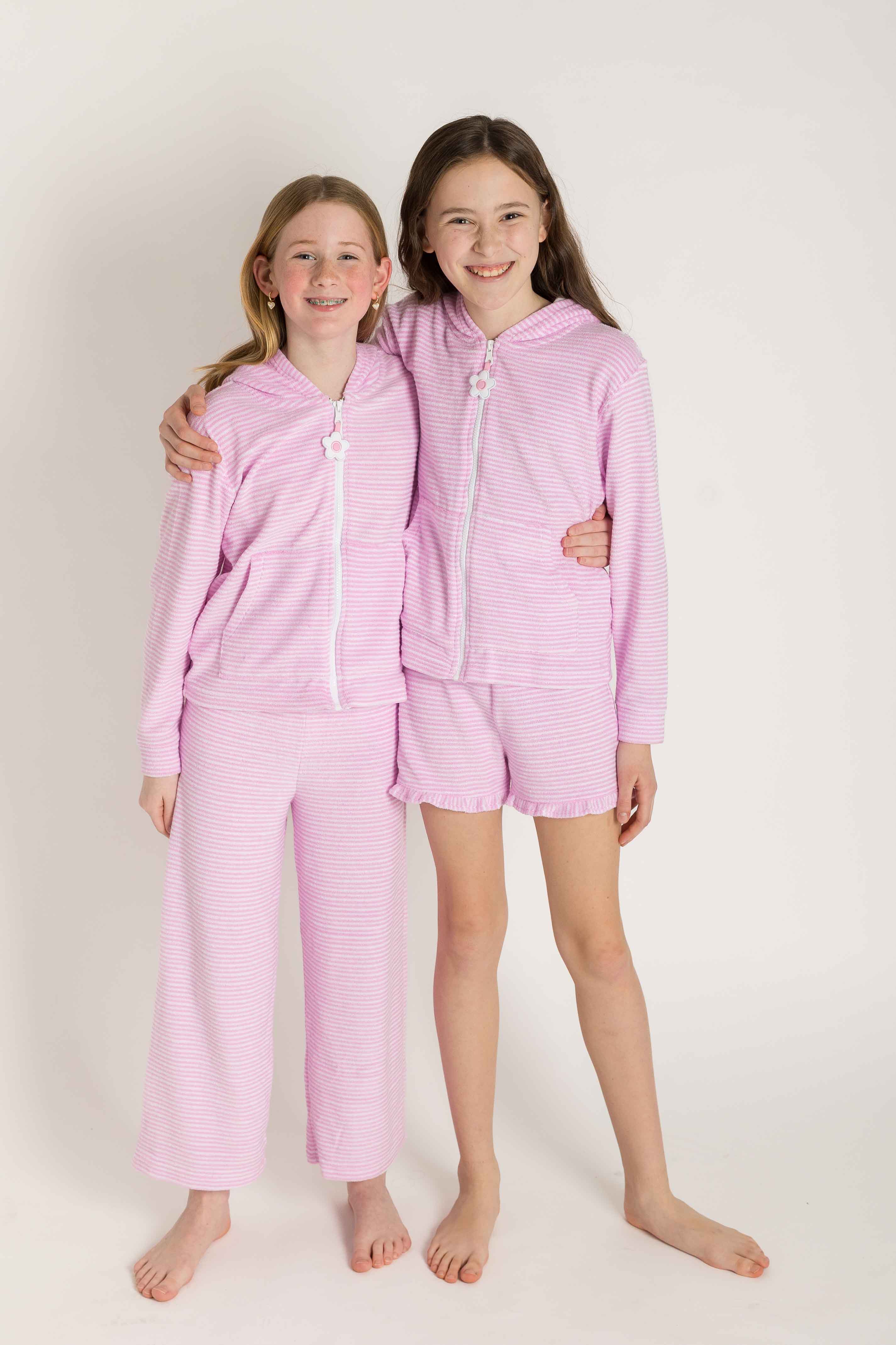 Two children wearing pink coverup sets on a white background