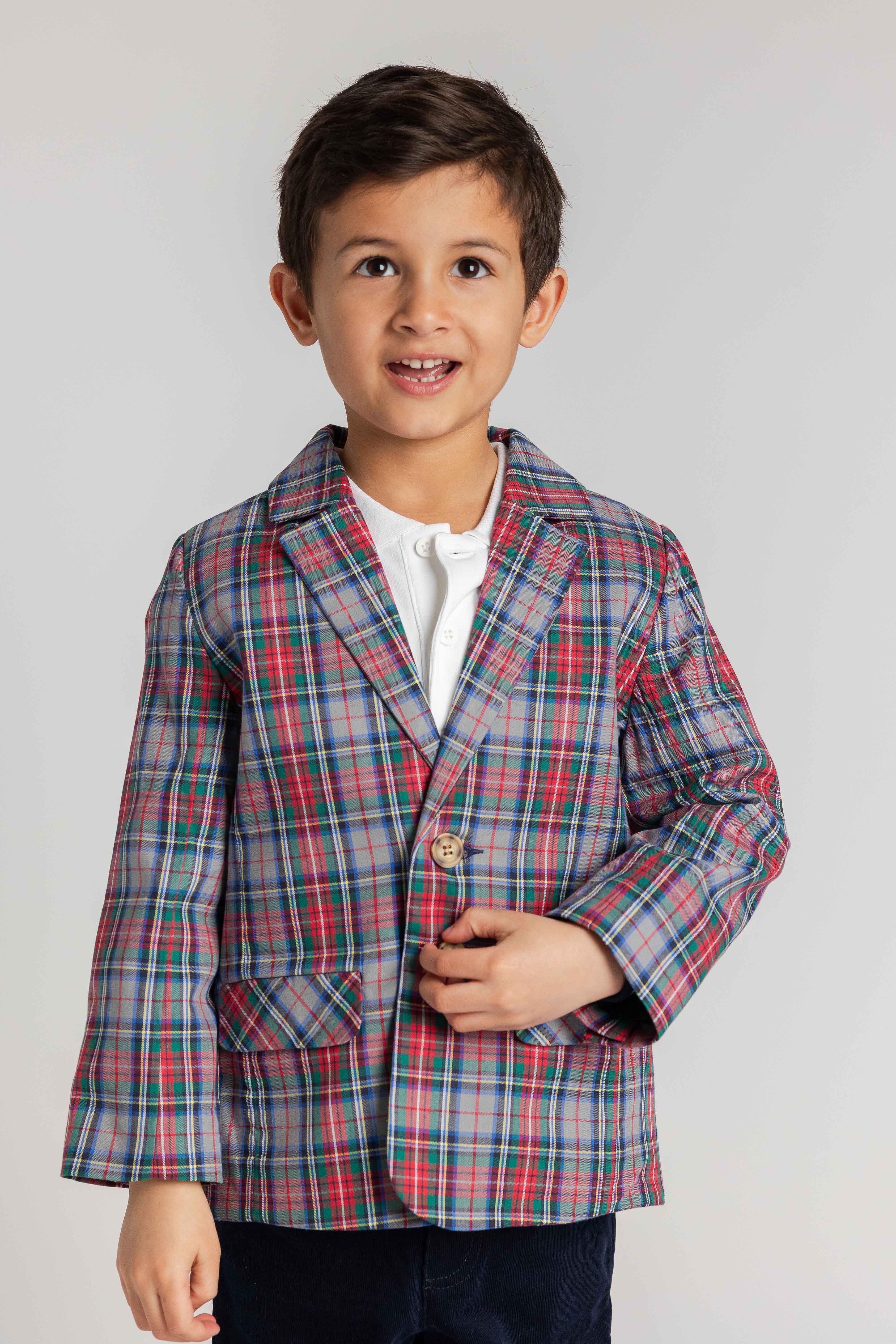 Child wearing a plaid jacket on a plain background