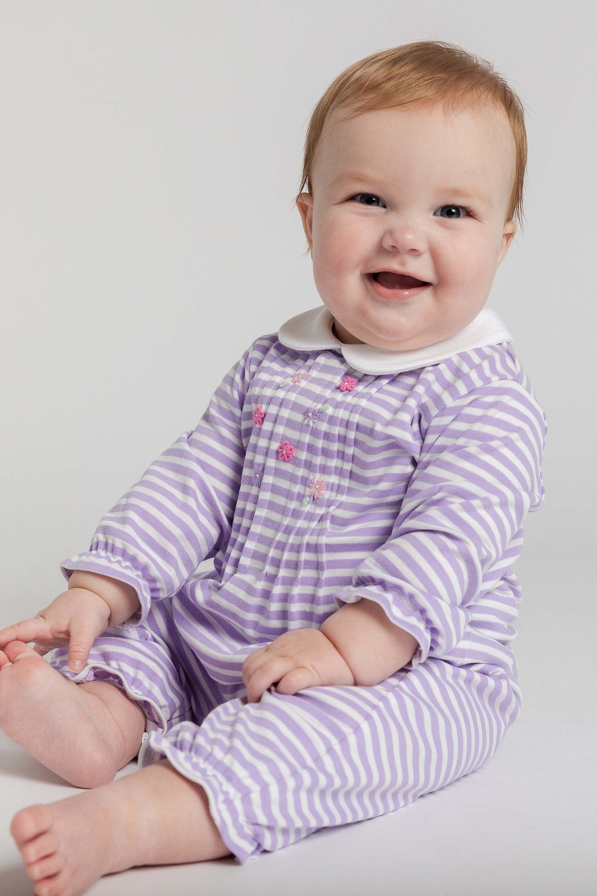 Baby wearing a purple and white striped outfit on a plain background