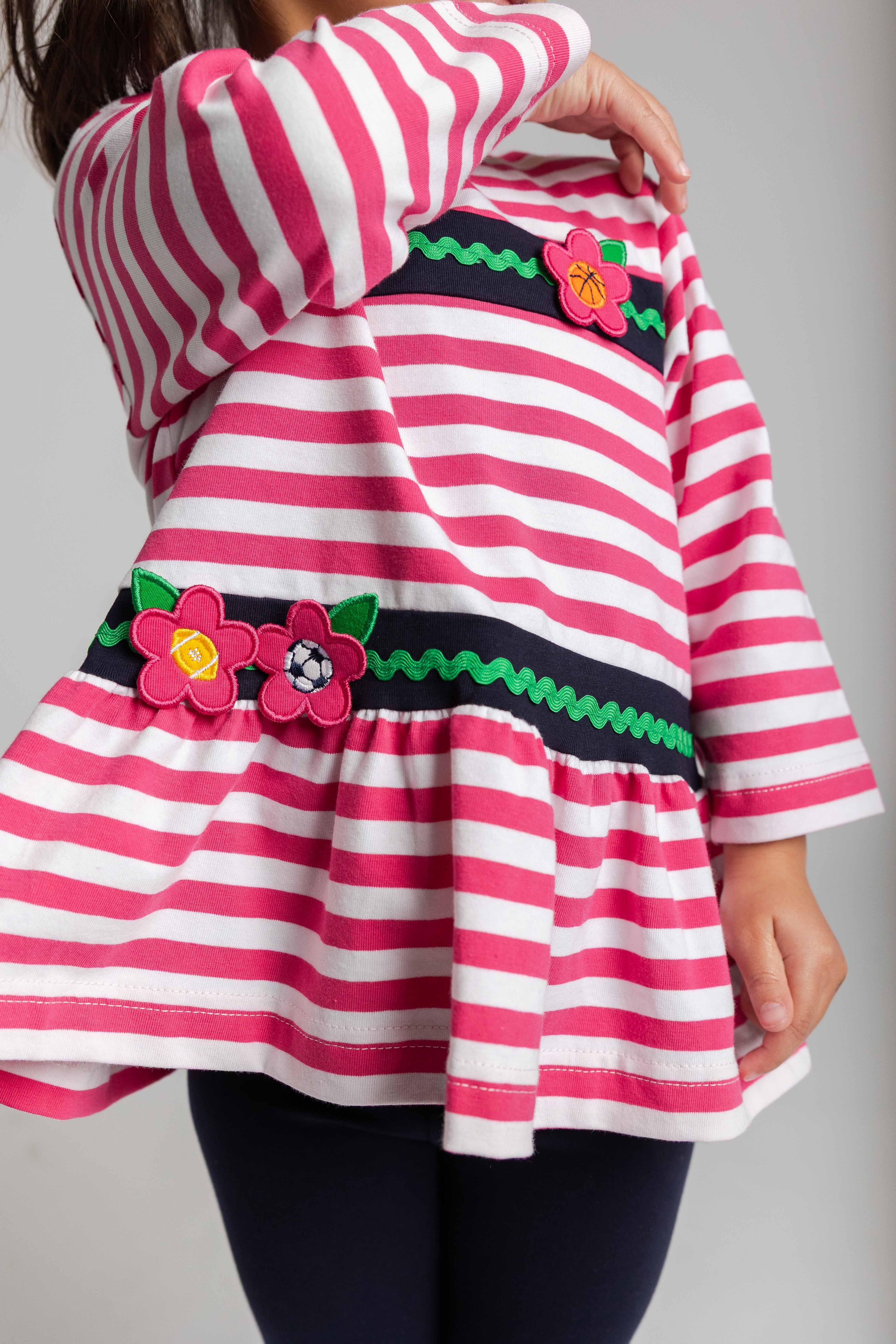 Pink and white striped shirt with floral appliqués on a plain background