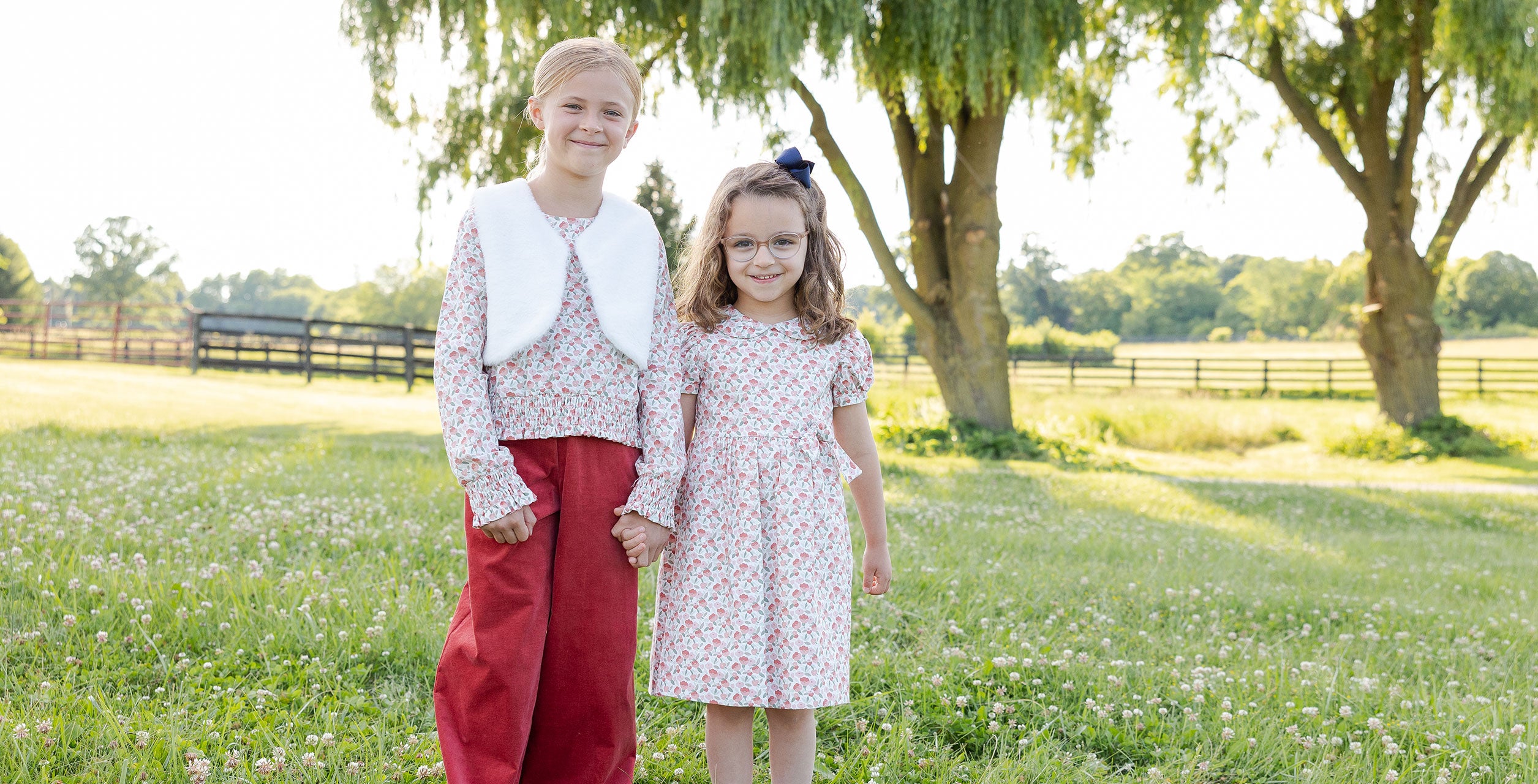 two young girls in a field in coordinating sibling styles