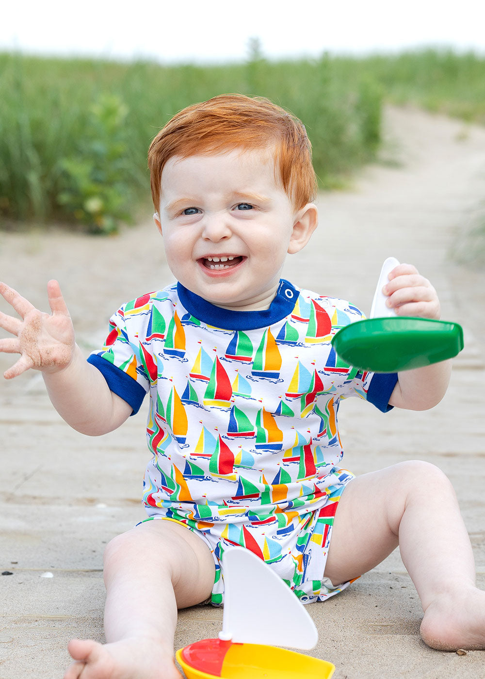 toddler boy on boardwalk in sailboat print shortall