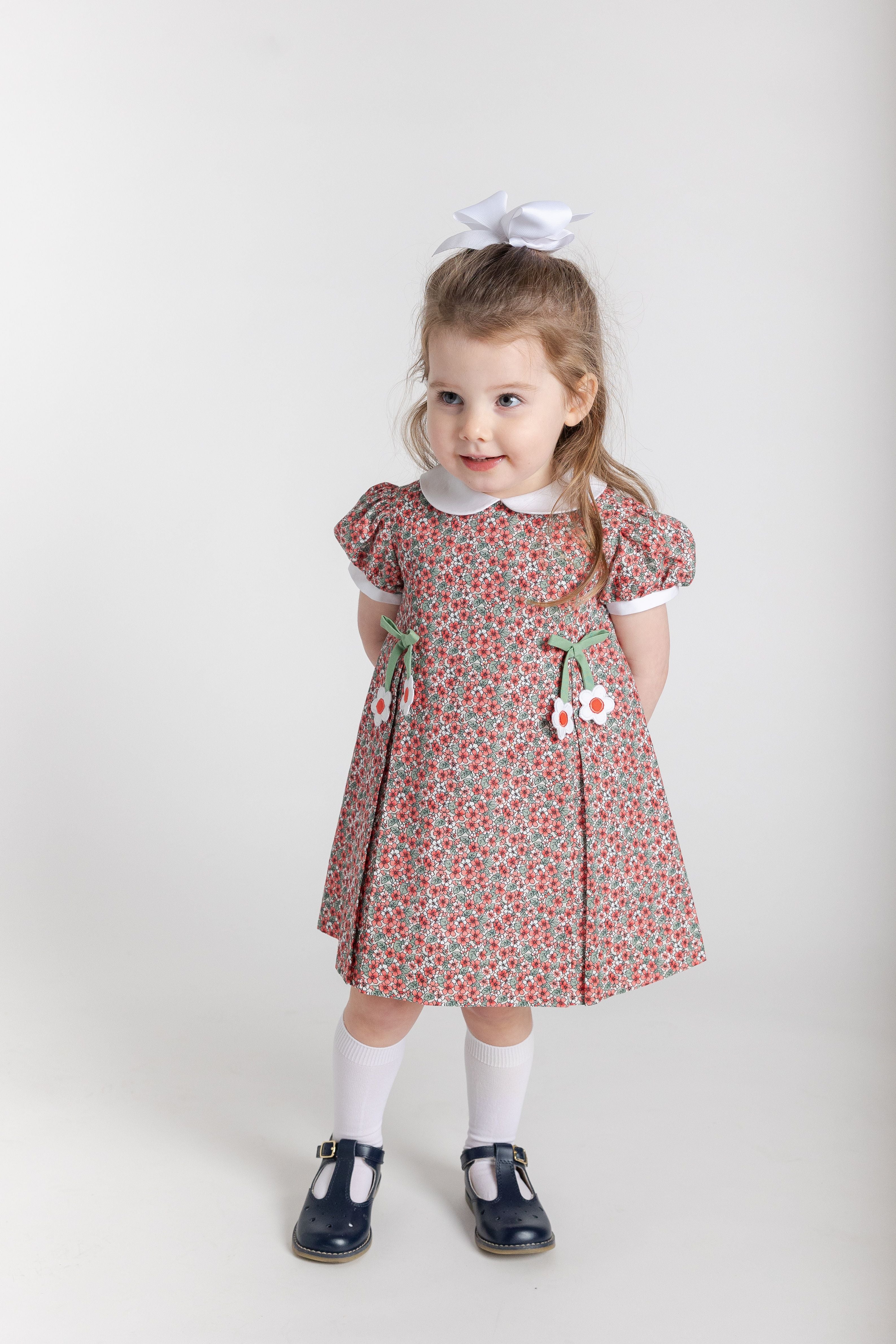 Young girl wearing a floral dress with white socks and black shoes