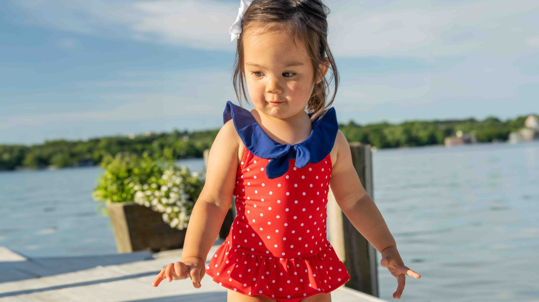 young girl in blue cherry swim suit with bucket