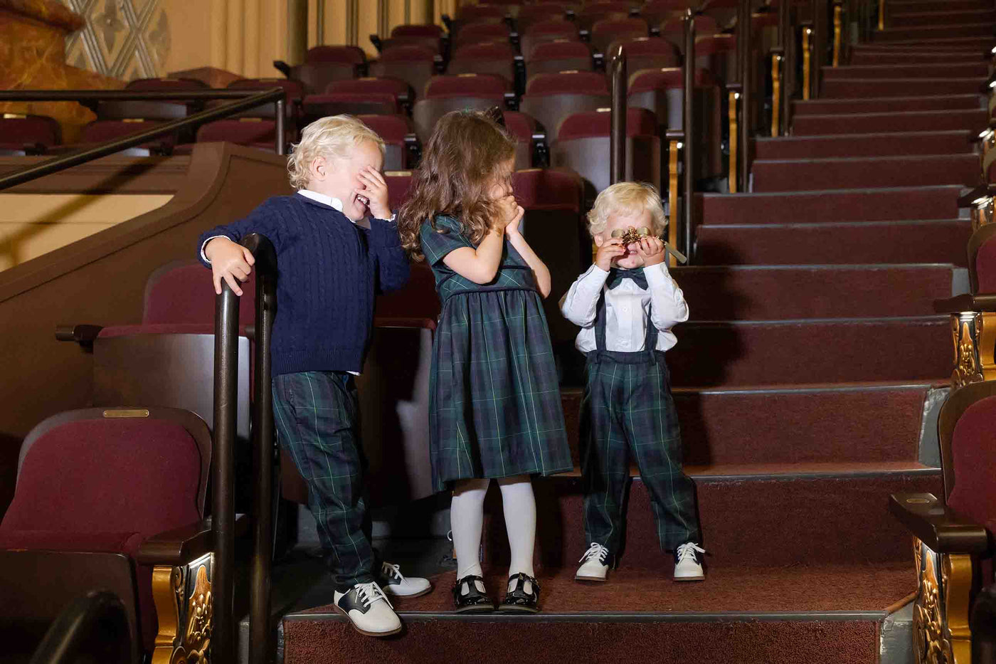 three children in a theater with opera glasses