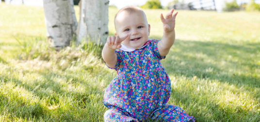 baby girl with toy on blanket in grass