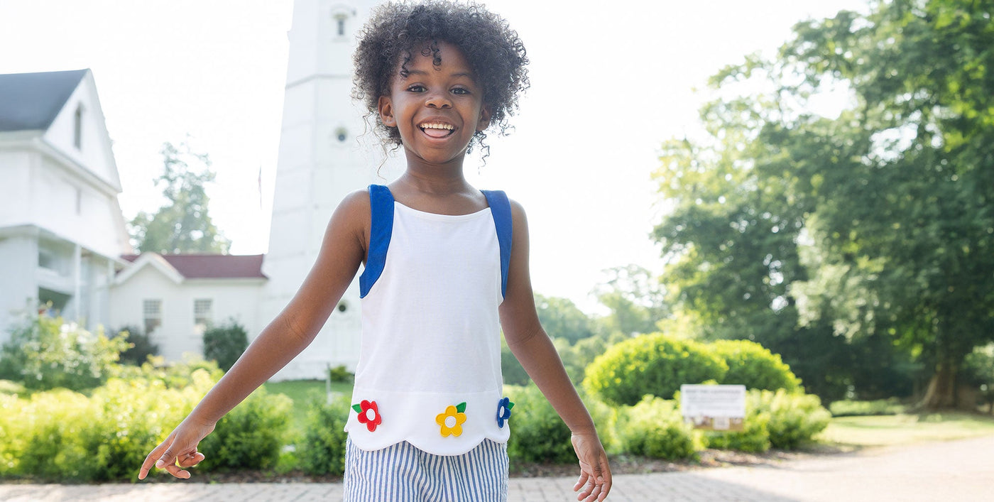 girl holding cherries to her ears in the grass