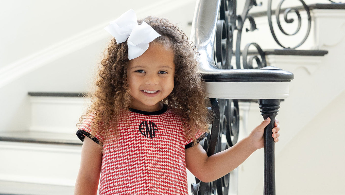 young girl in houndstooth dress on stairs