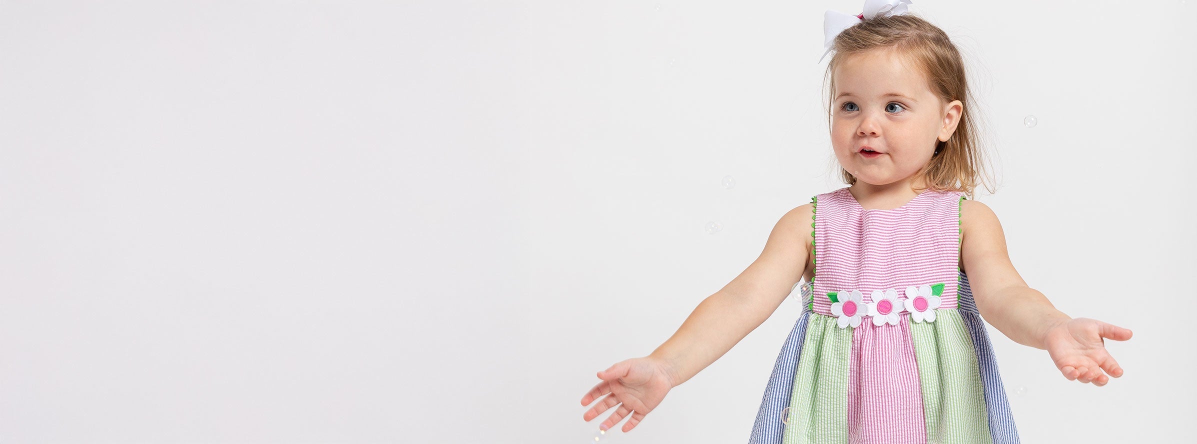 girl in stripe dress with flowers holding arms out