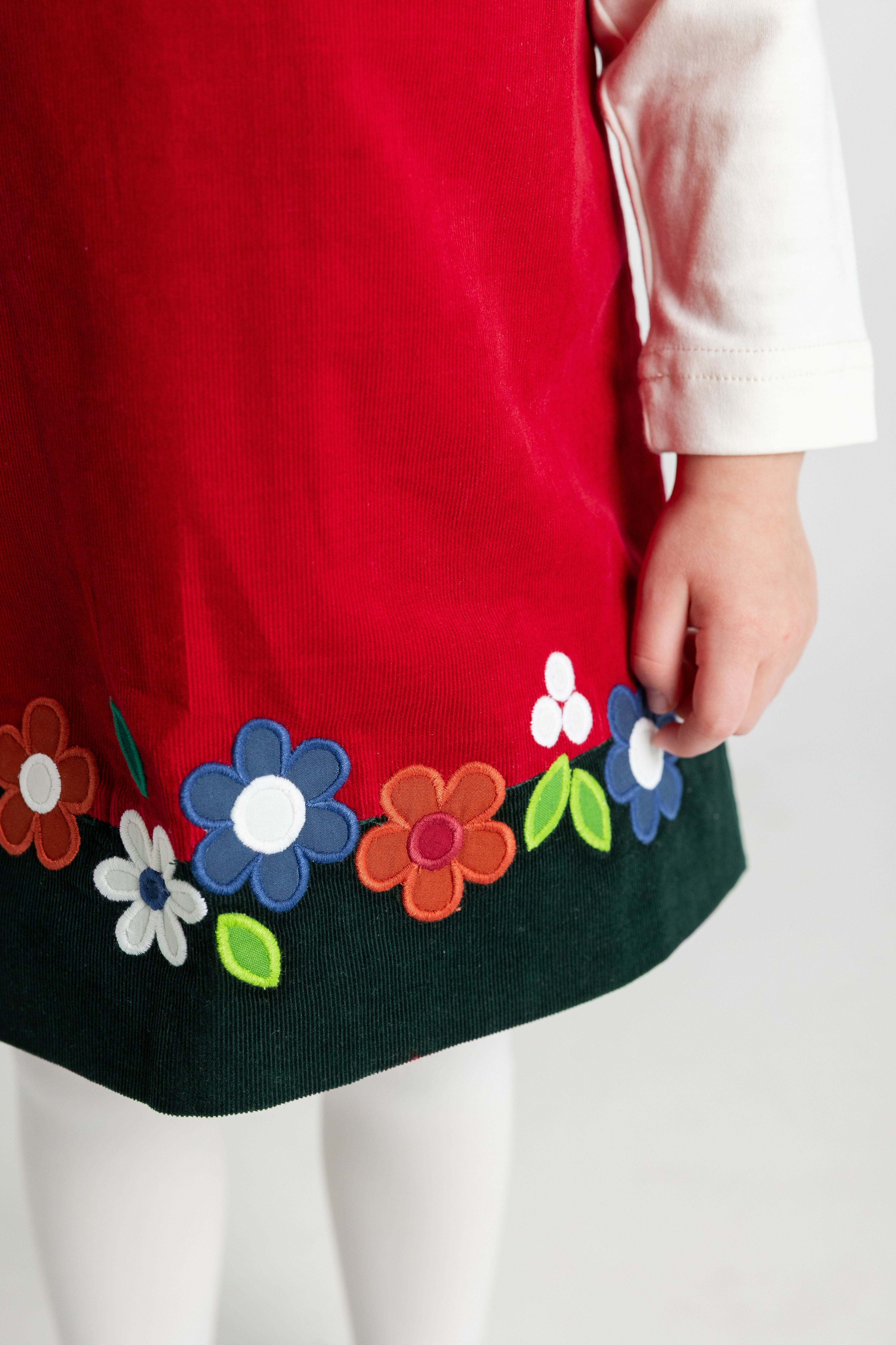close up of detail on red dress with colorful floral patterns on a white background