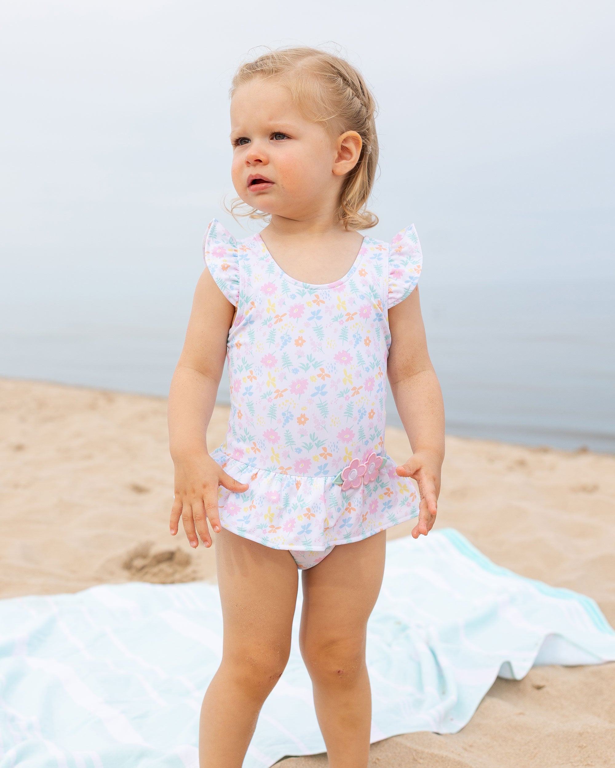 young girl at beach in flower print swimsuit