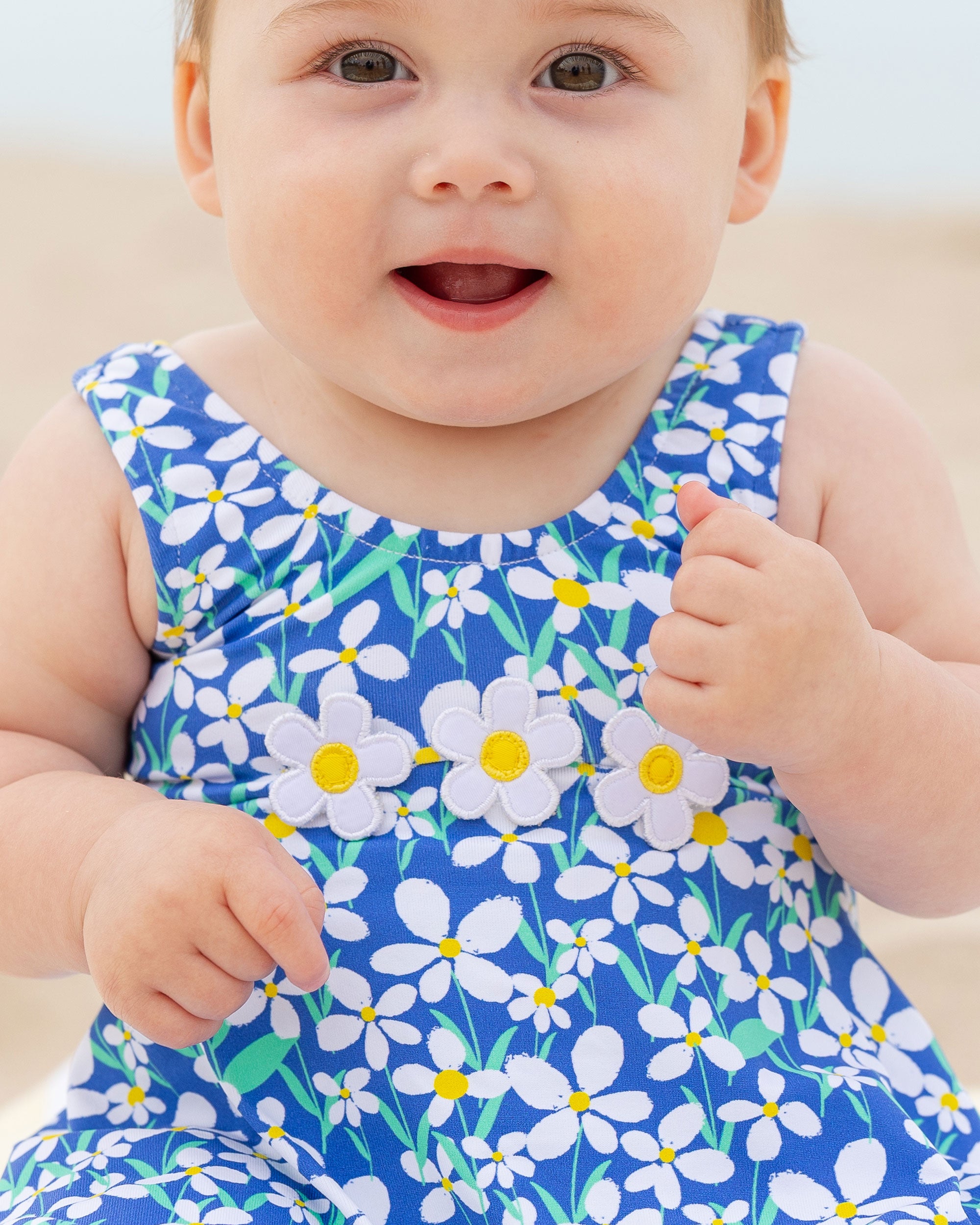 closeup of baby on beach wearing swimsuit with flowers and skirt