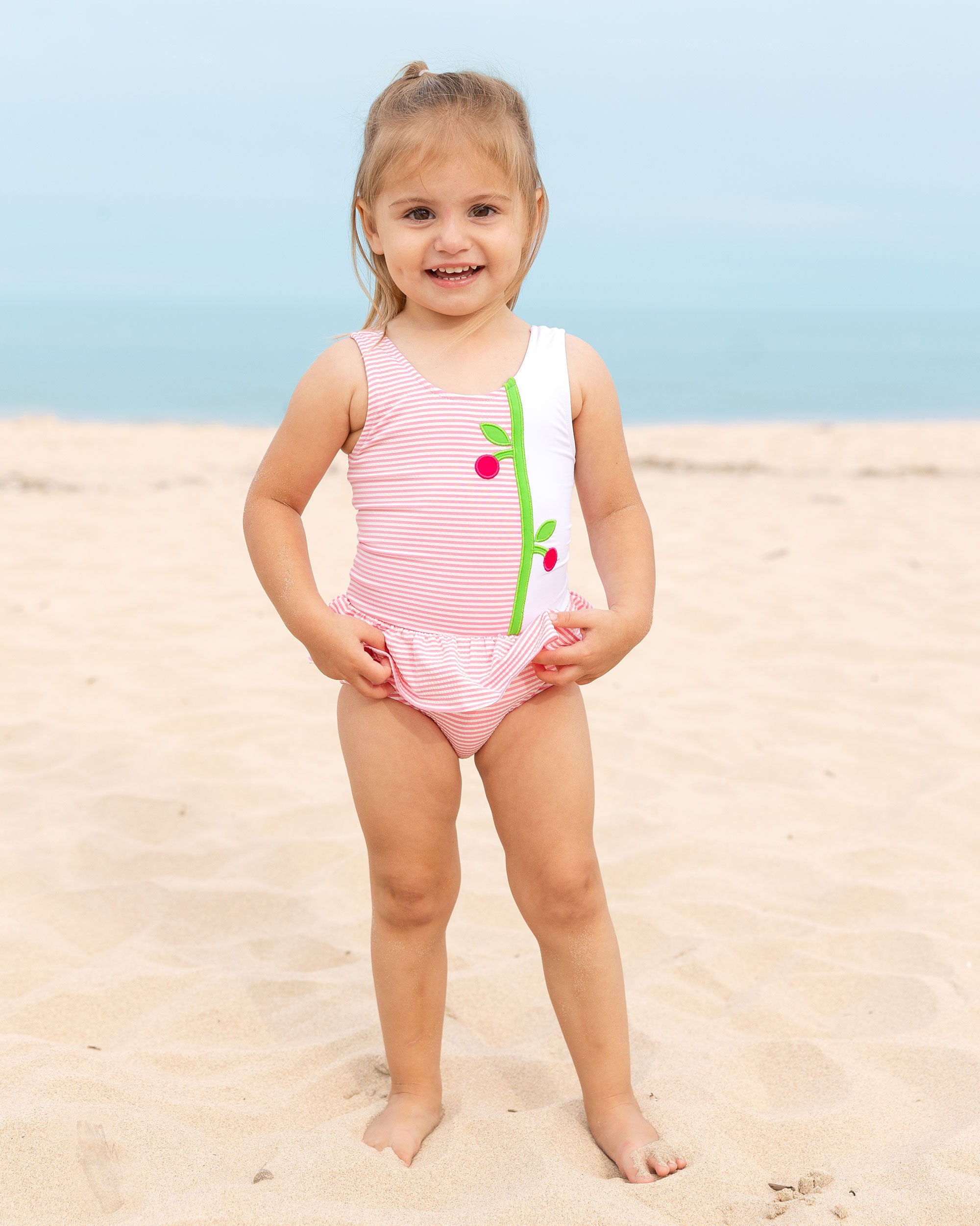 young girl on the beach wearing a seersucker suit with cherries