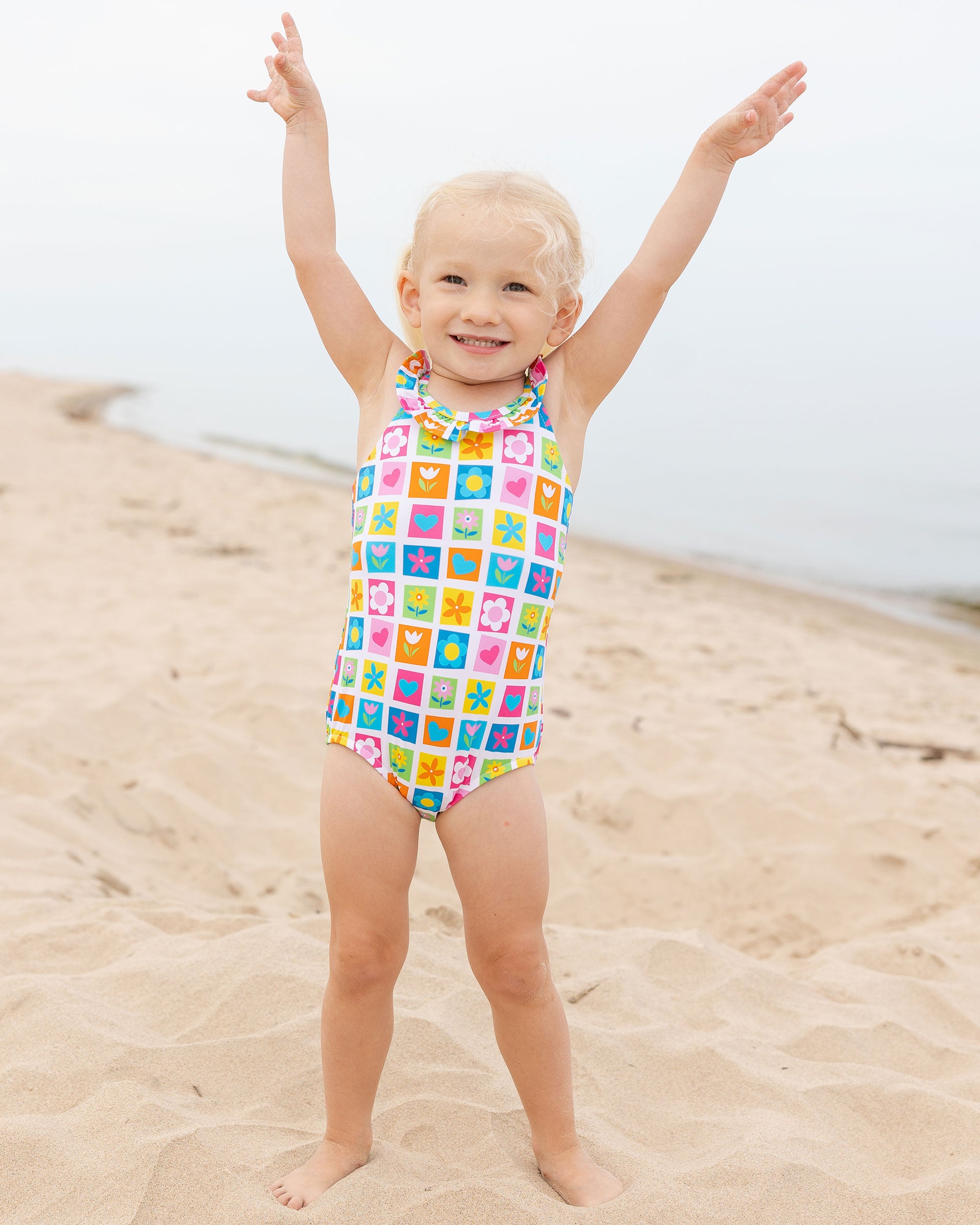 young girl on beach in patchwork floral swimsuit