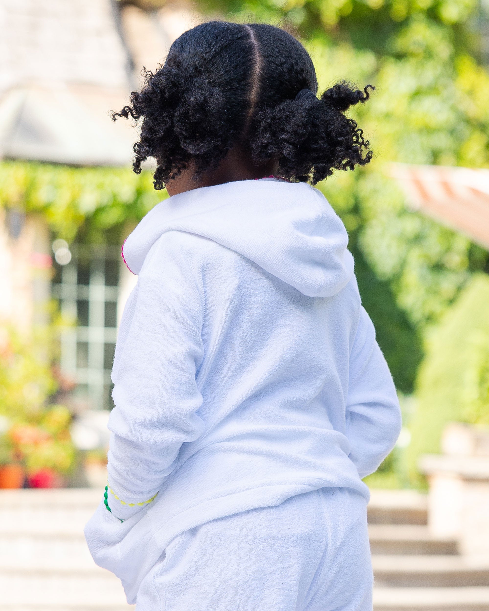 Back of person wearing a white hoodie with a blurred outdoor background