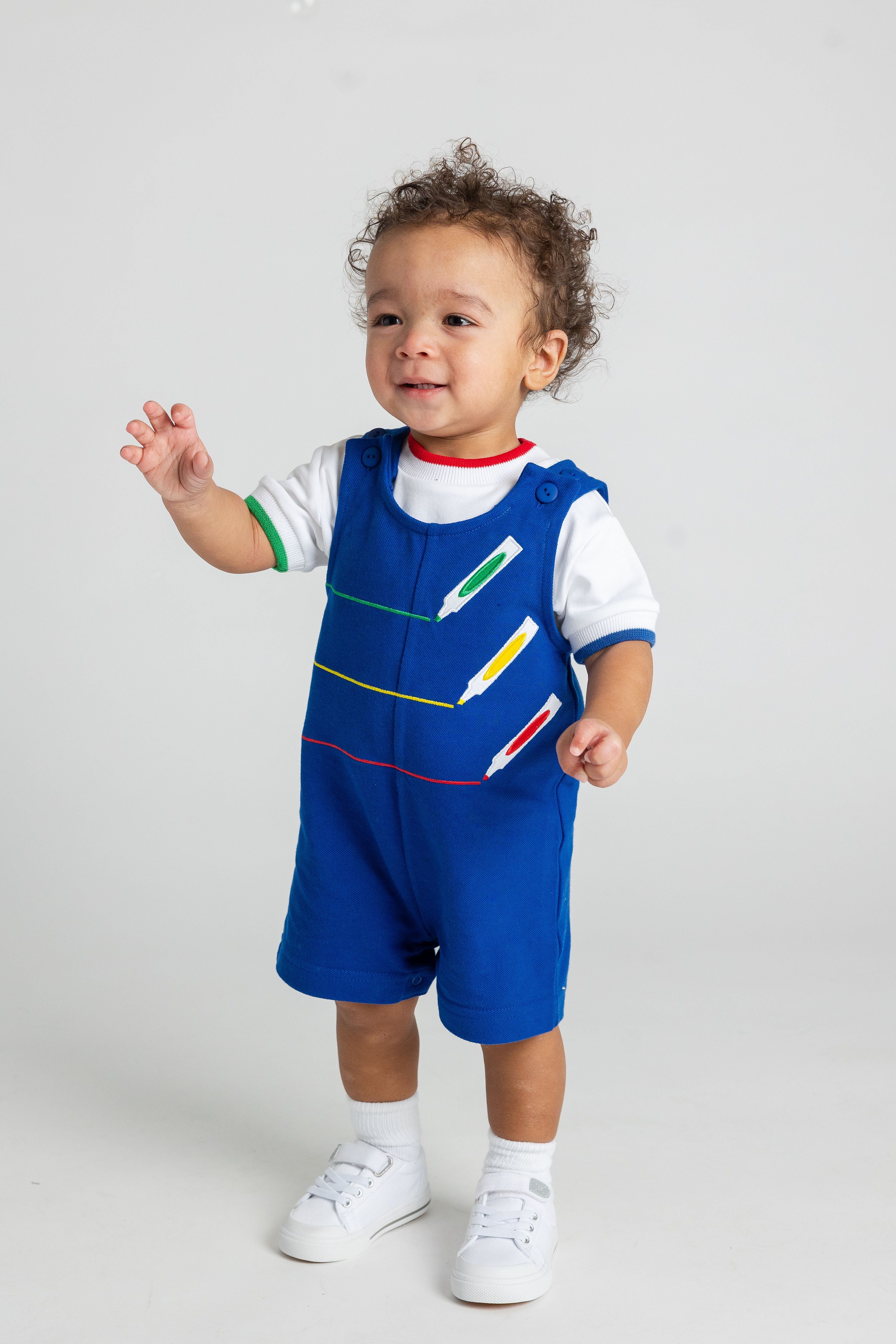 Child wearing a blue outfit with colorful pencil designs on a white background