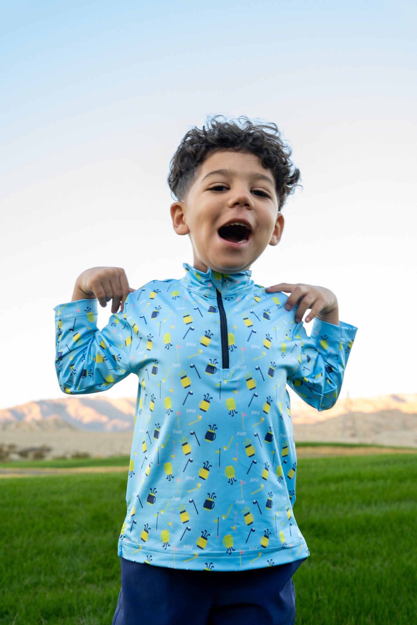 Child wearing a blue jacket with a mountainous landscape in the background