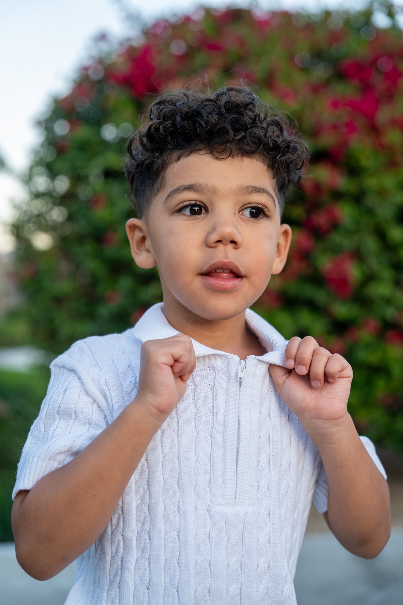 Child wearing a white outfit with a blurred floral background