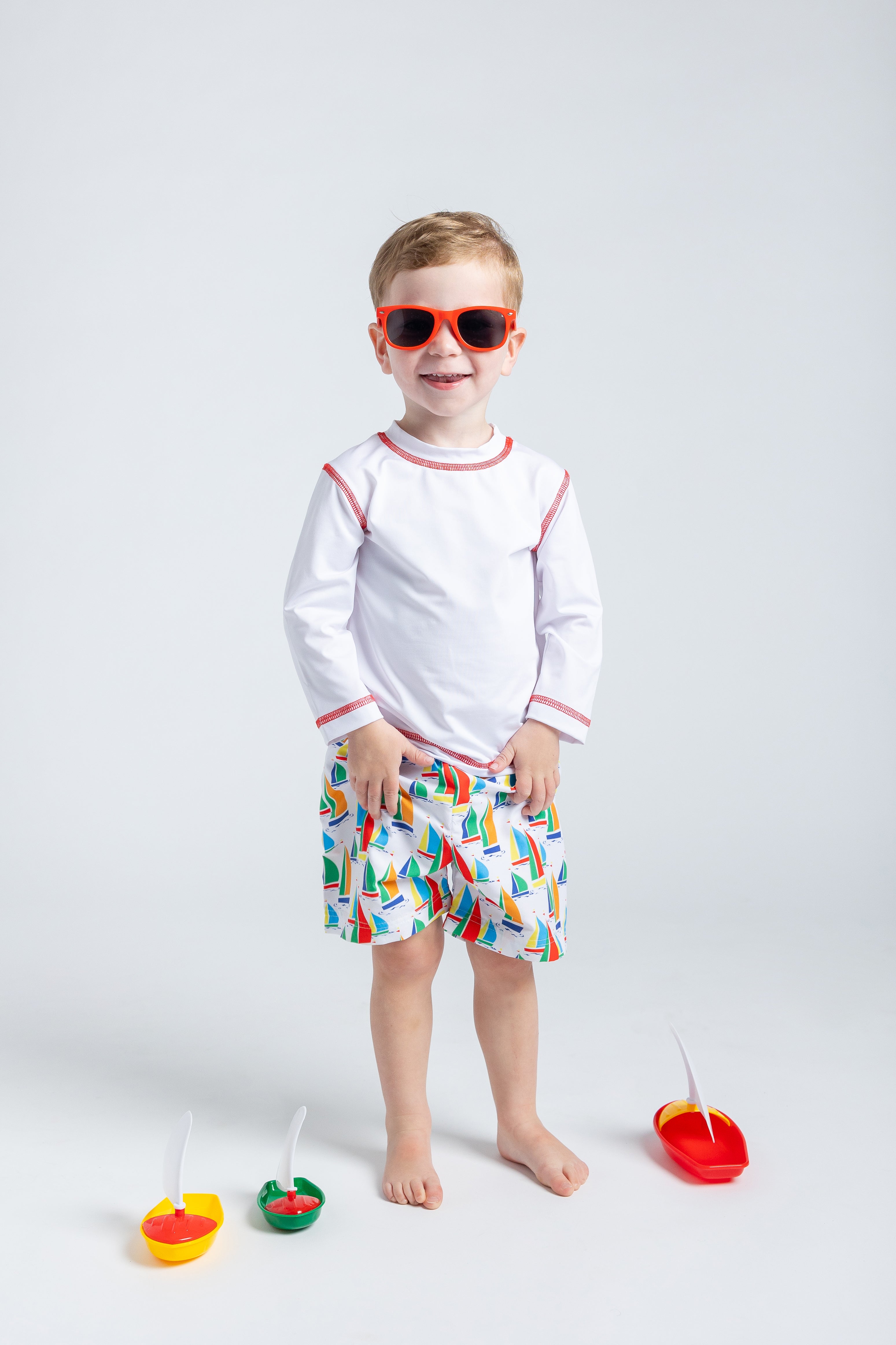 boy in swim trunks with sailboats
