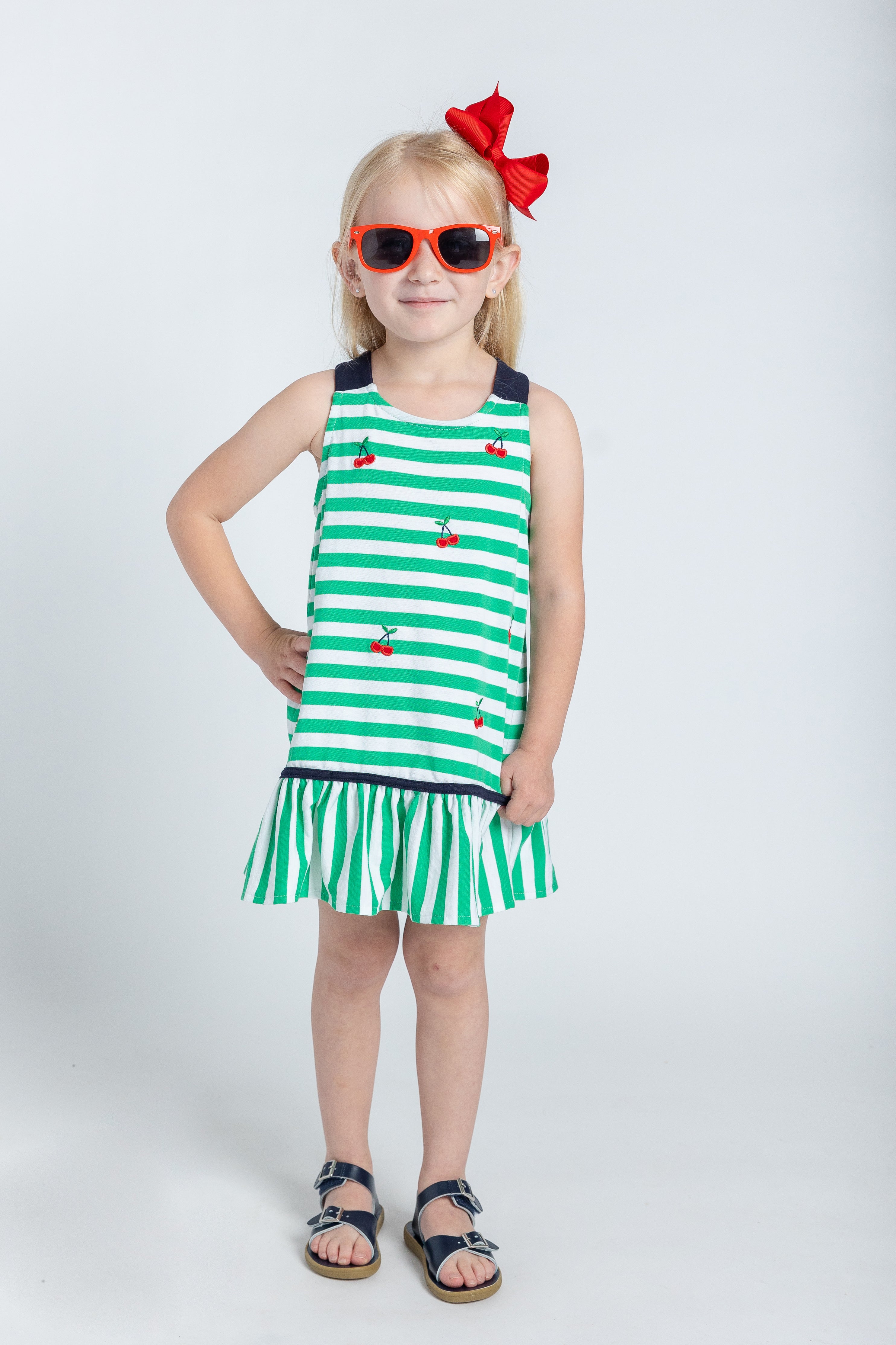 model in green and white stripe dress with cherries and a red hair bow