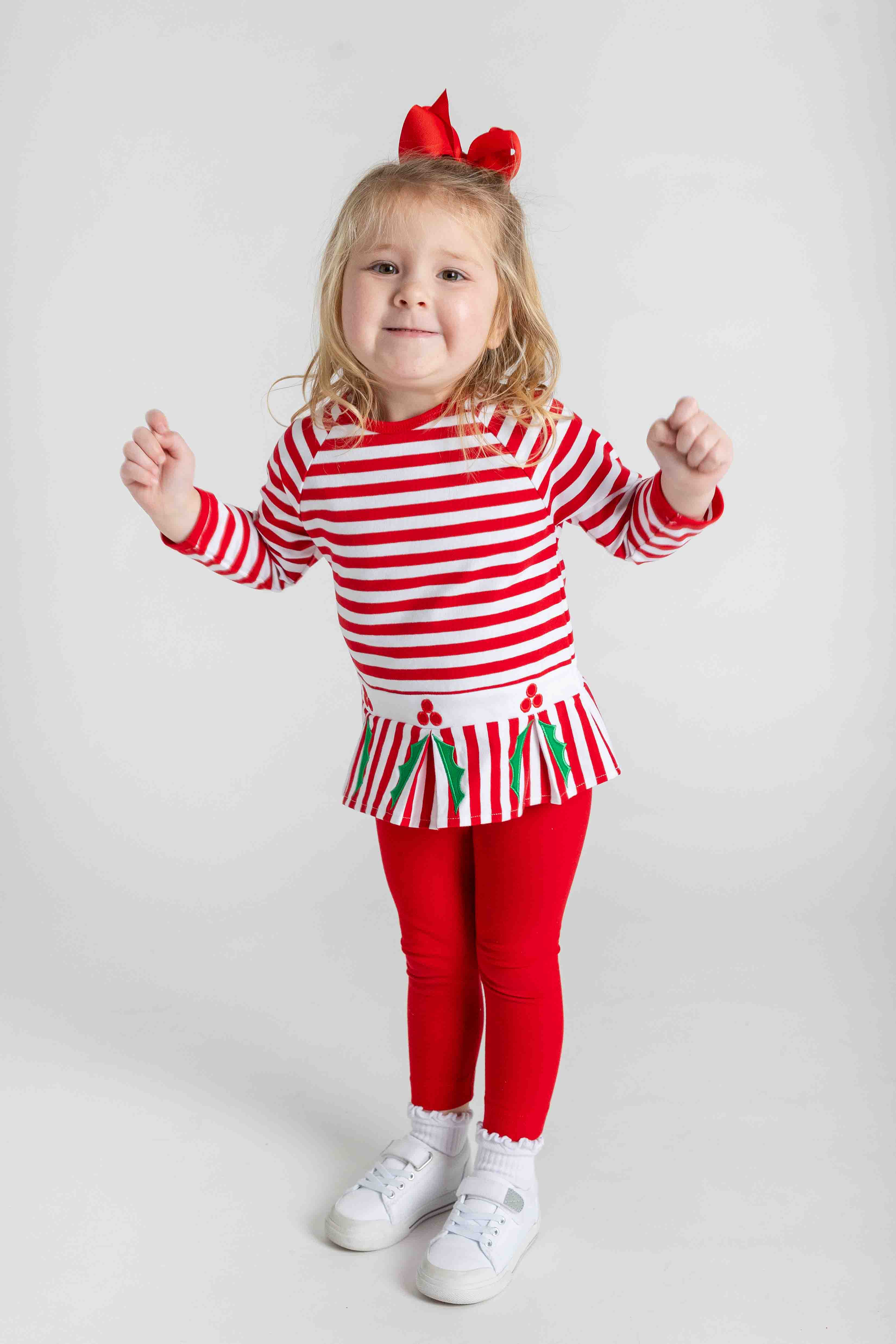 Child wearing a red and white striped outfit with a skirt on a white background