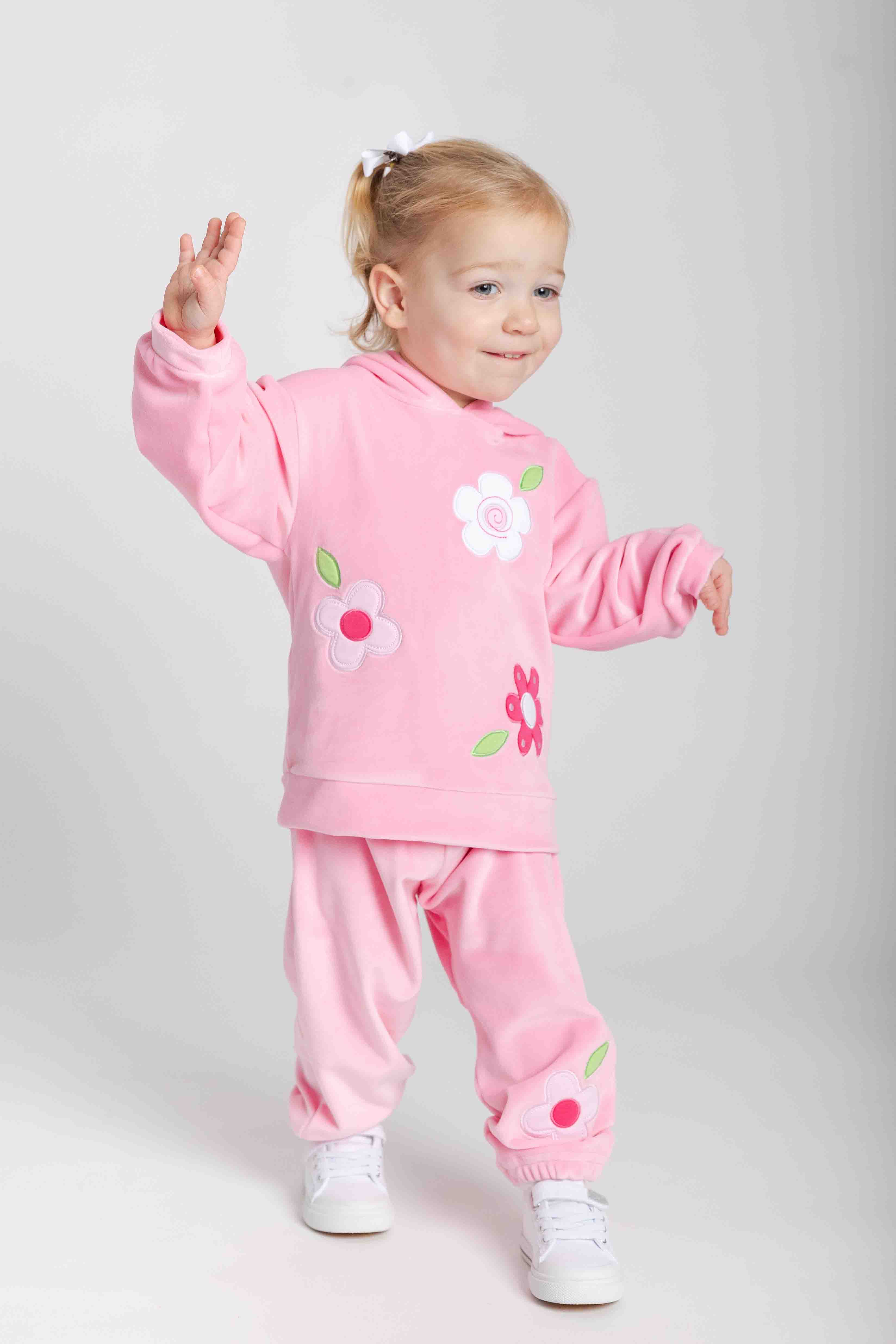 Child wearing a pink outfit with floral designs on a light gray background