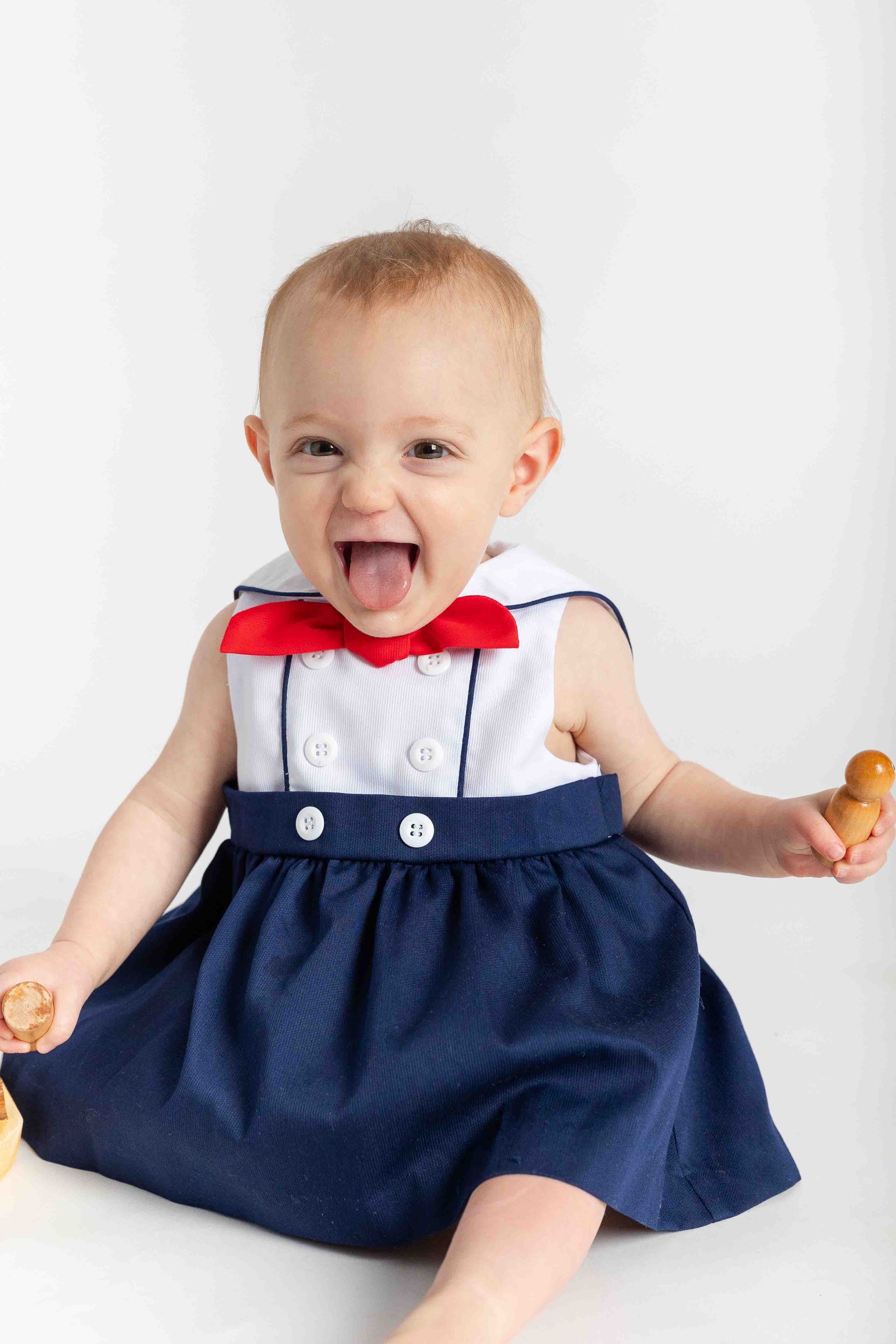 baby sitting in sailor romper with toys