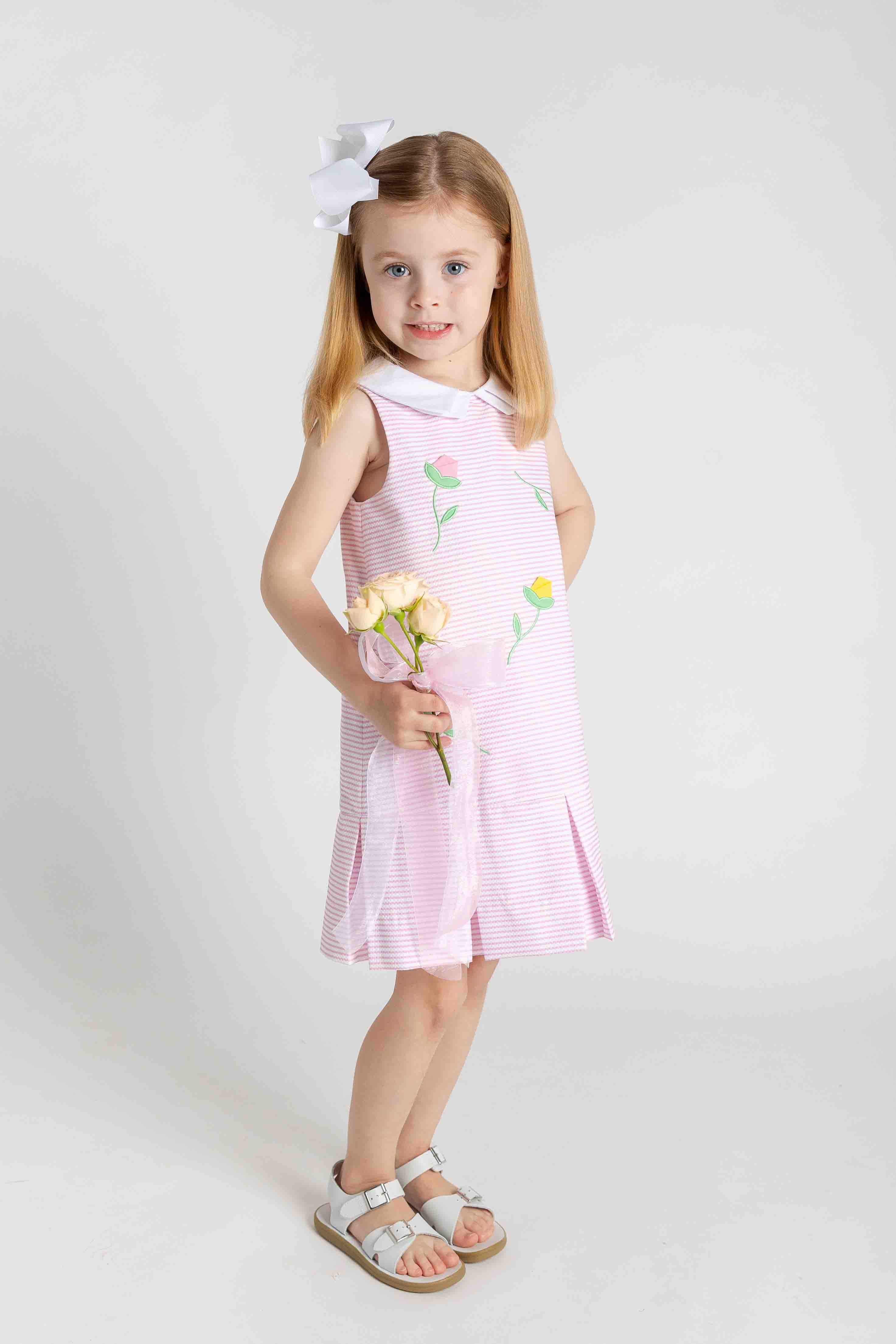 Young girl wearing a pink dress with floral patterns on a white background