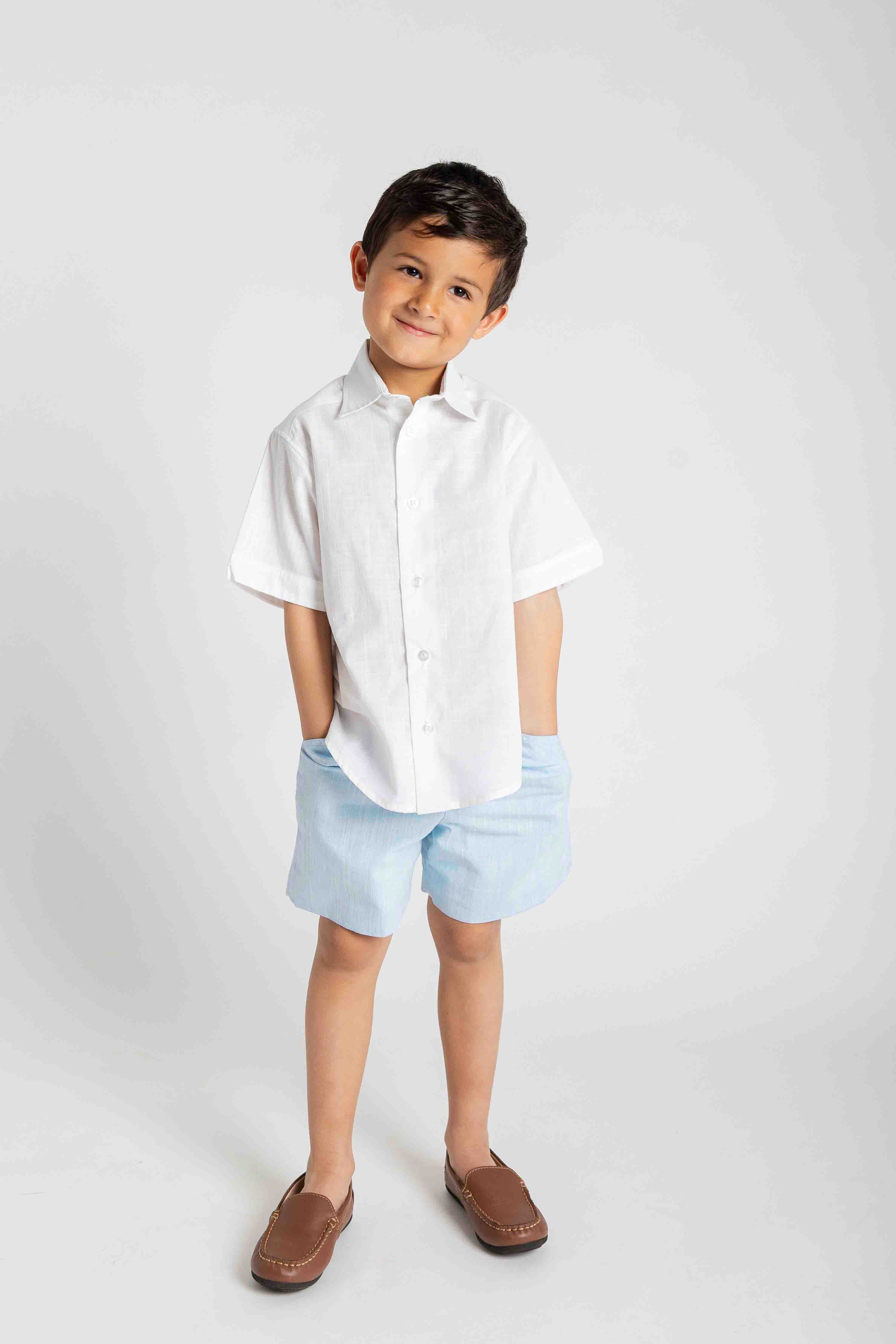 Child wearing a white shirt and light blue shorts on a white background