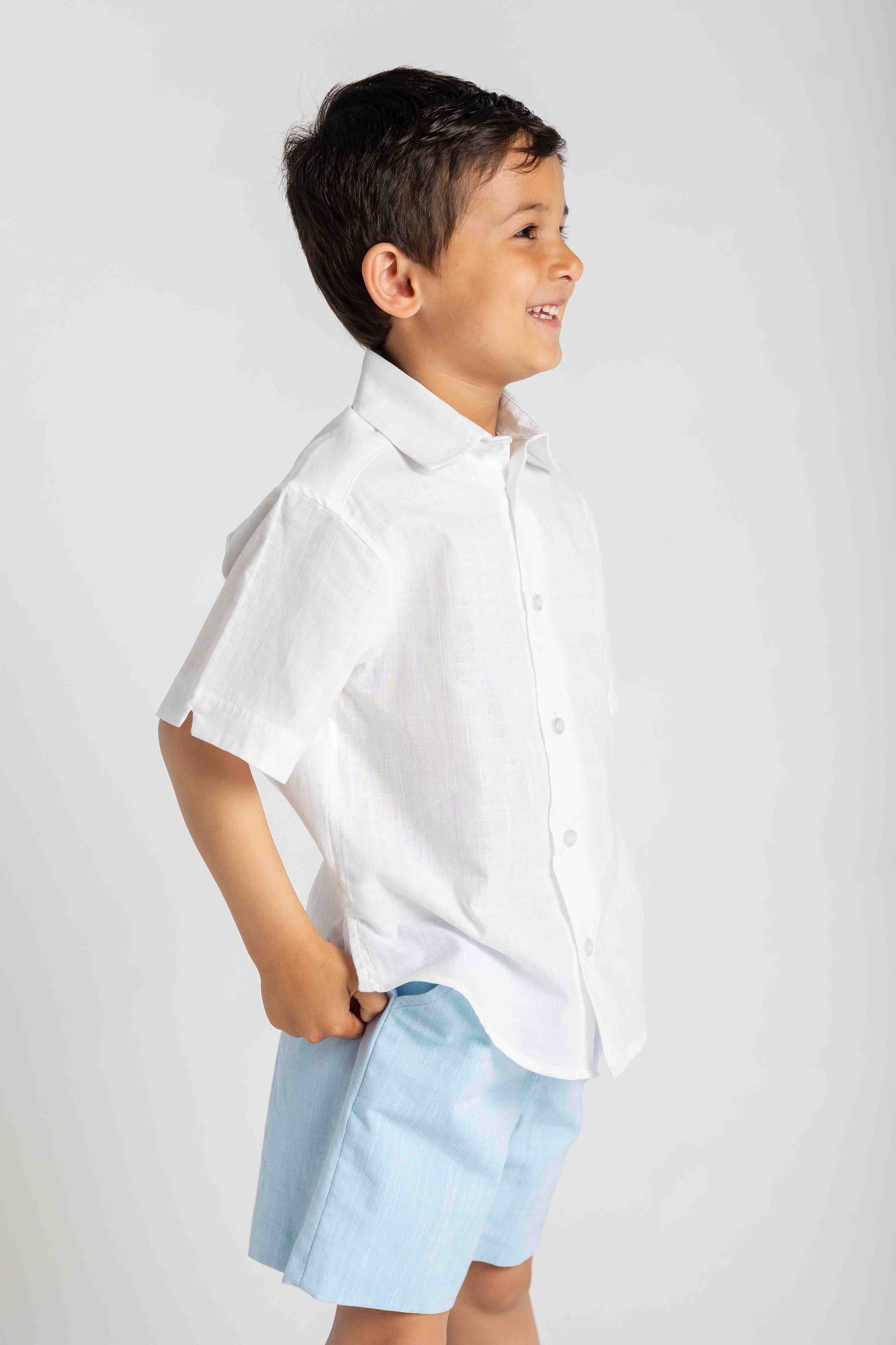 Child wearing a white shirt and light blue shorts on a white background