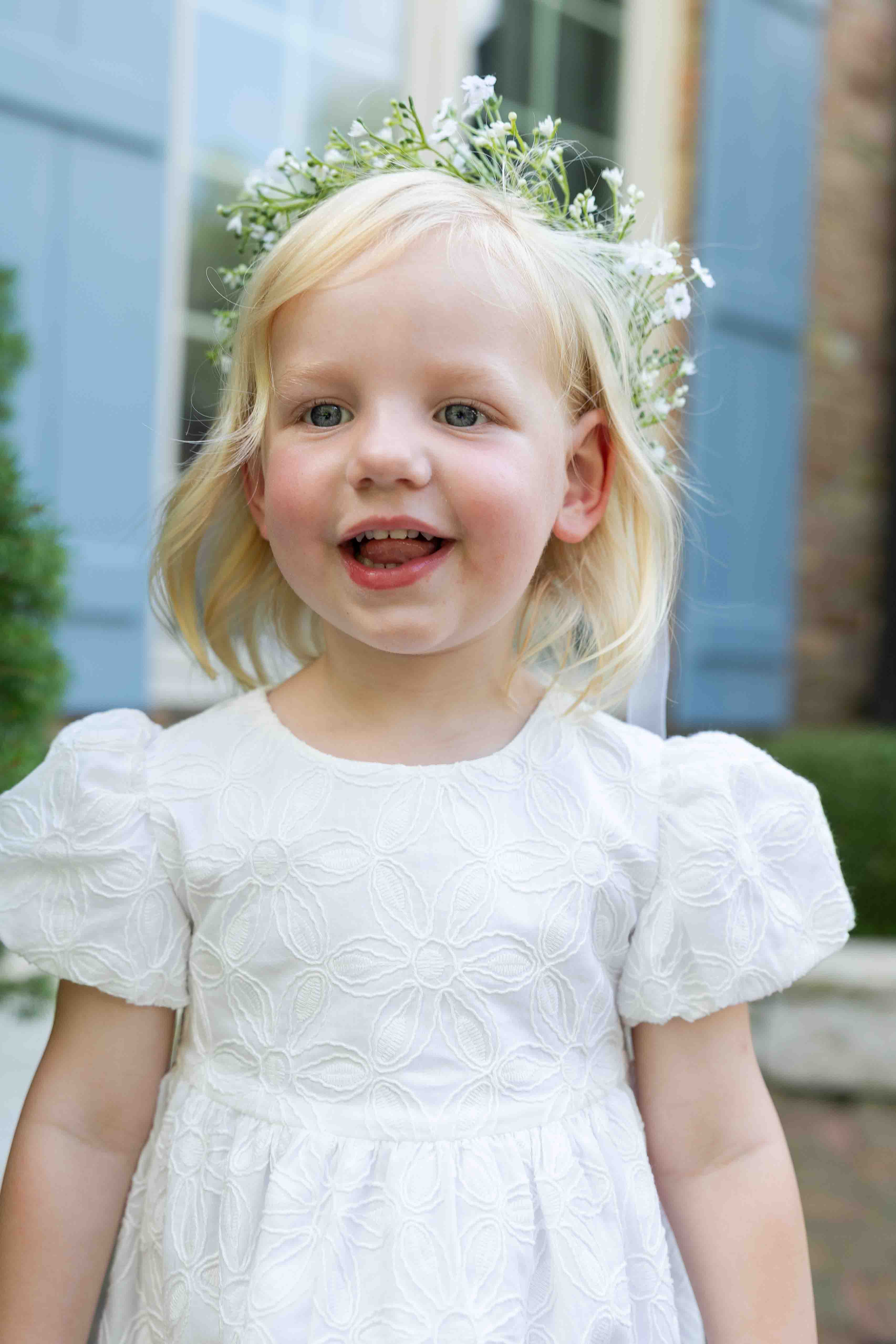 Young girl in a white dress with a floral headband outdoors