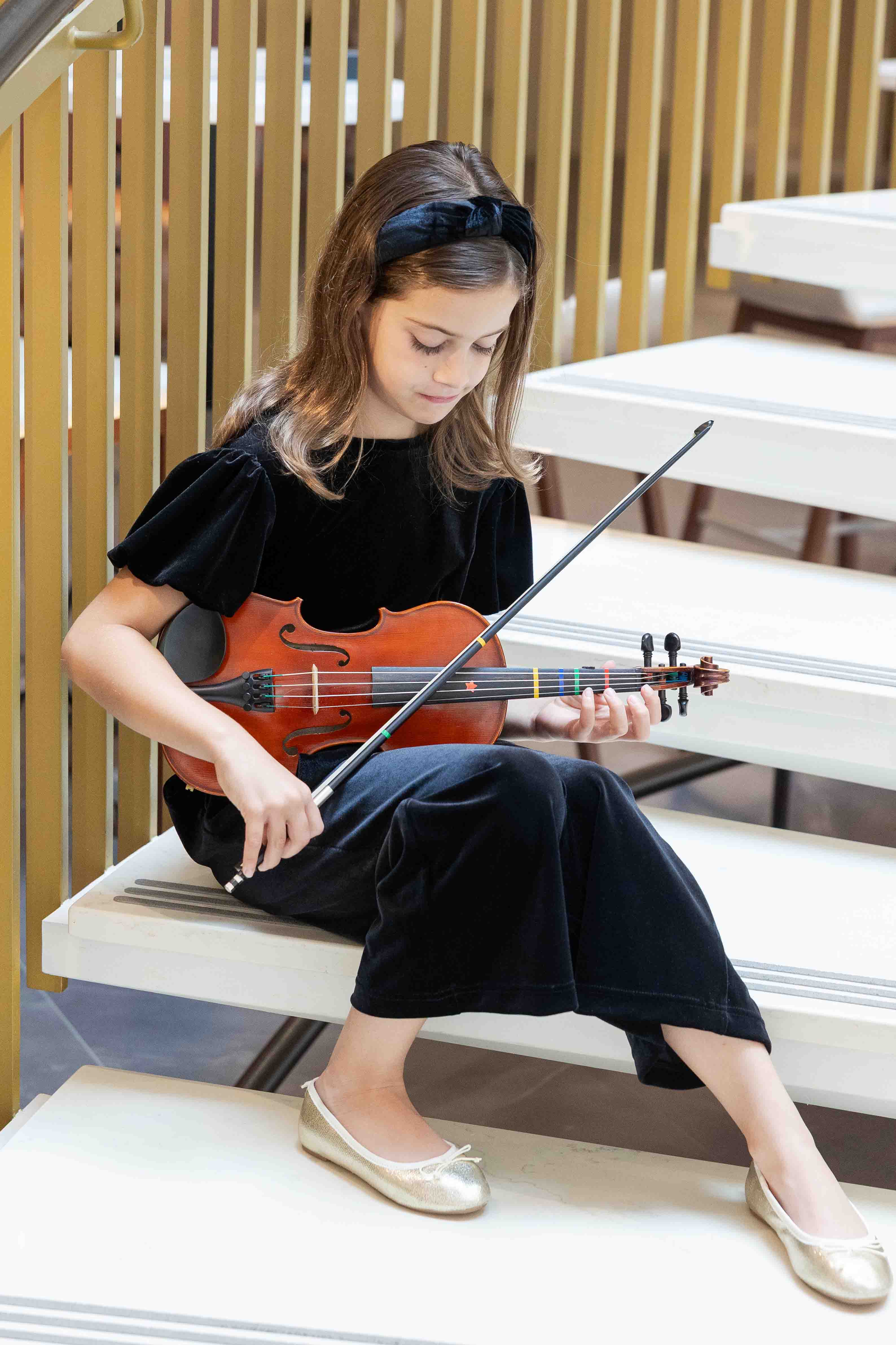 Young girl playing violin on a staircase