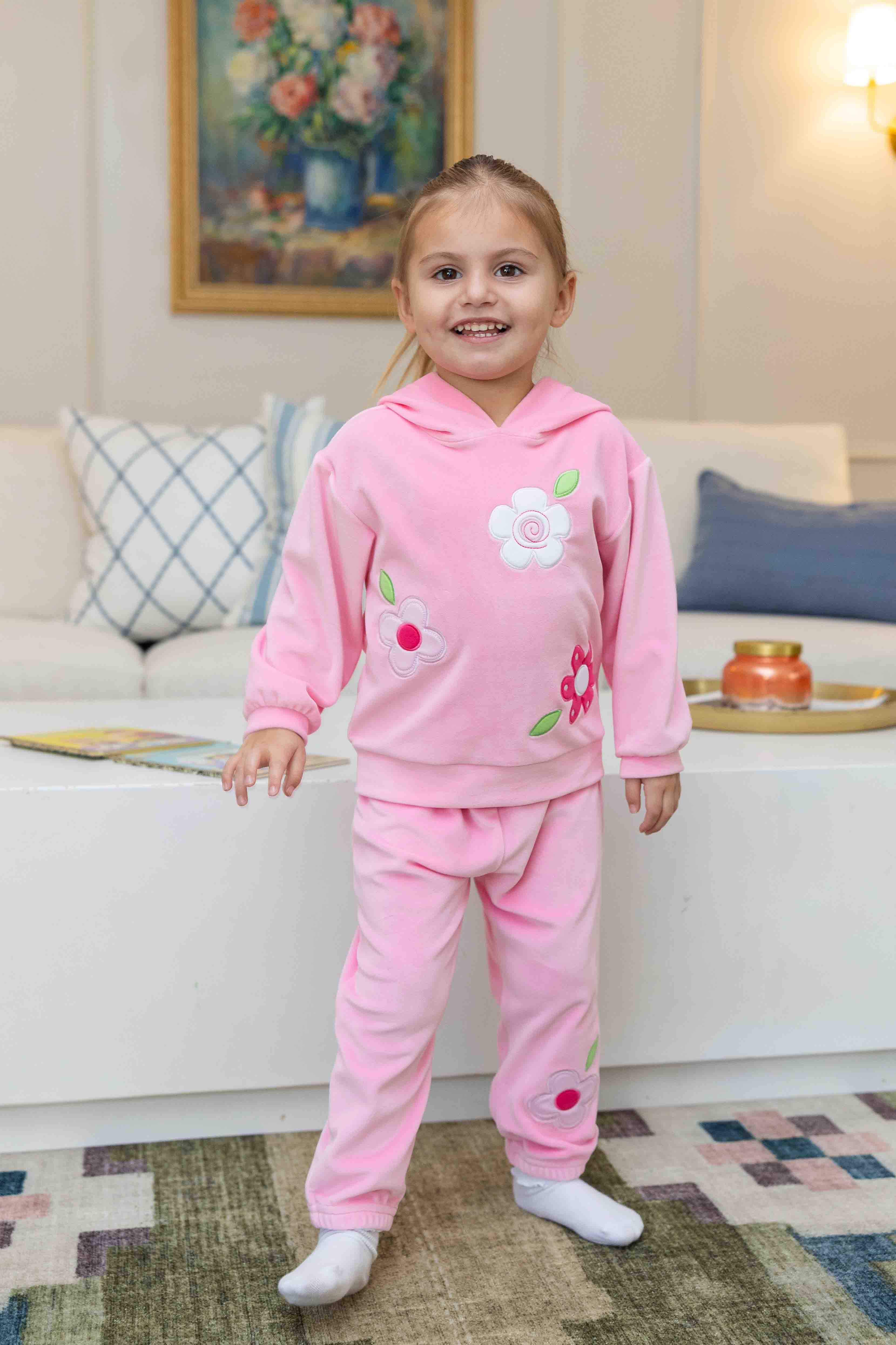 Child wearing a pink outfit with floral designs in a living room setting