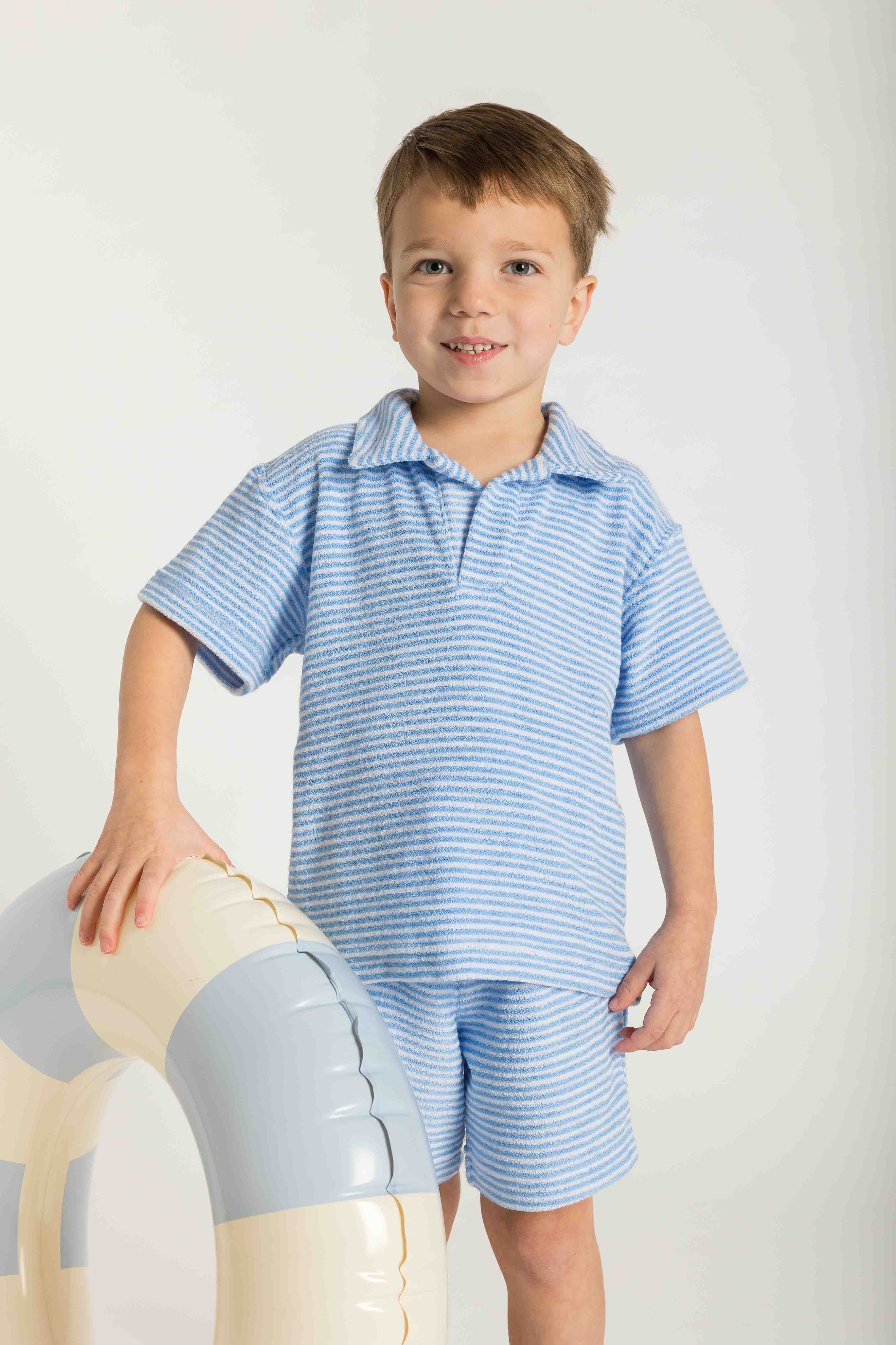 Young boy wearing a blue striped shirt and shorts on a white background