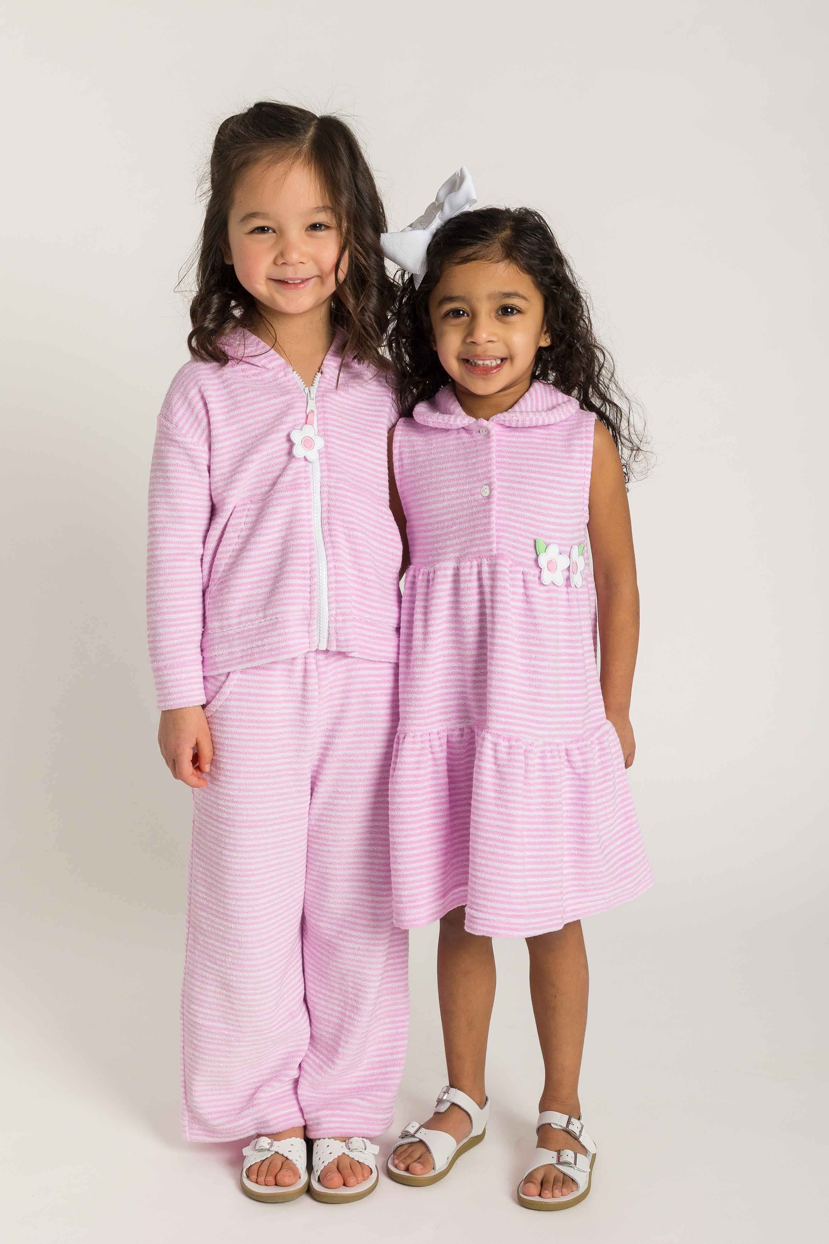 Two young girls wearing matching pink outfits on a white background