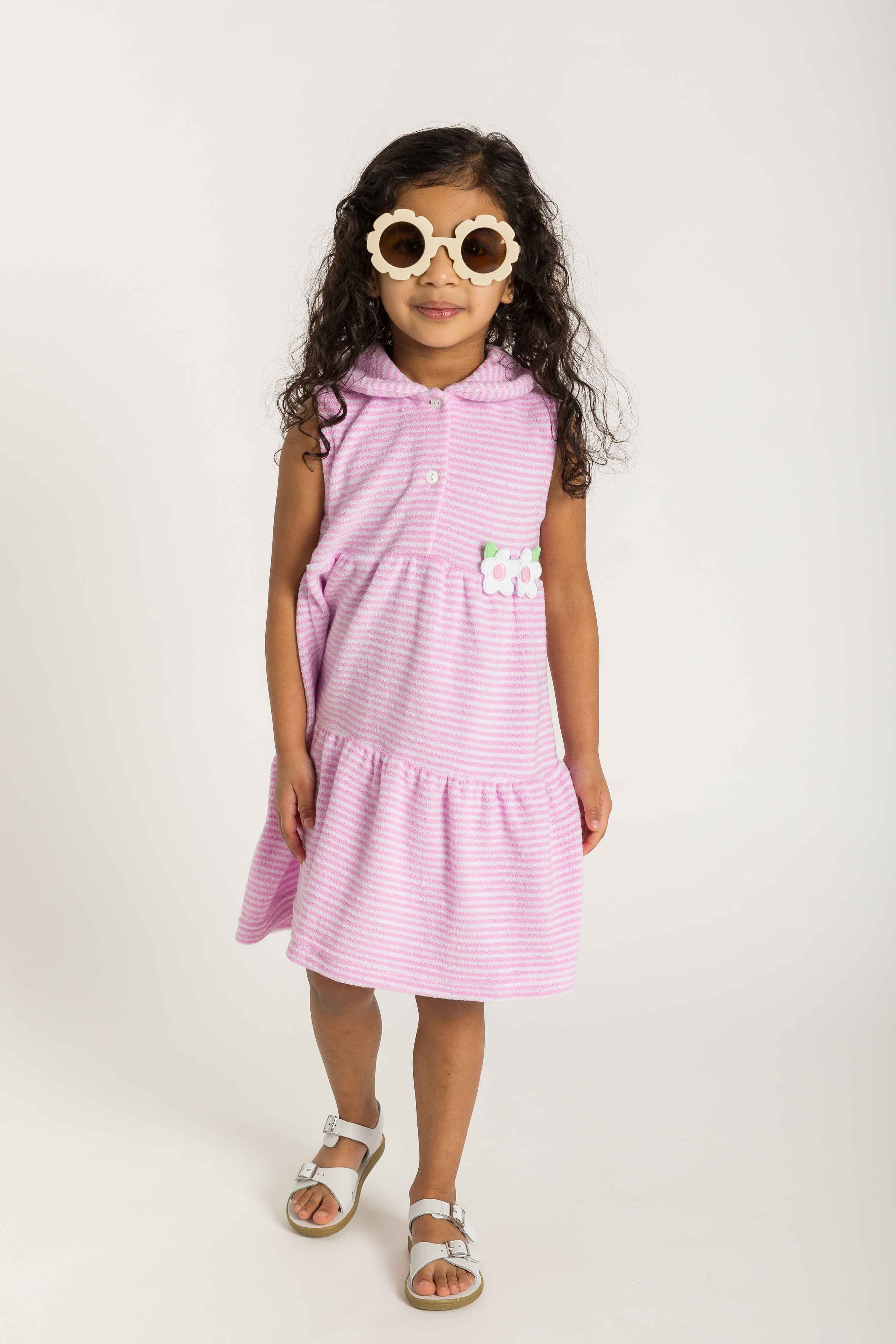 Young girl wearing a pink striped dress with sunglasses on a white background