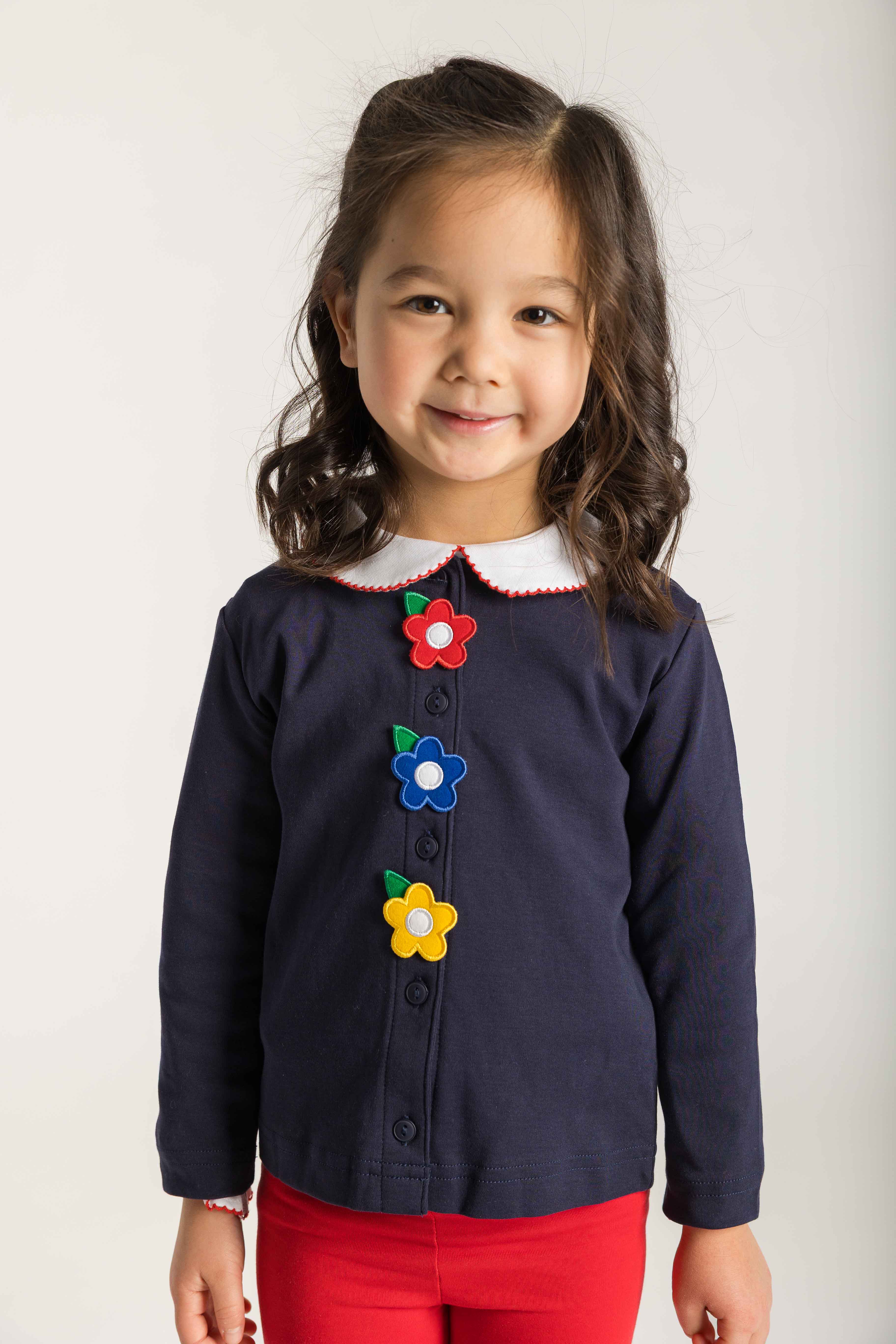 Child wearing a navy cardigan with colorful flower buttons on a white background