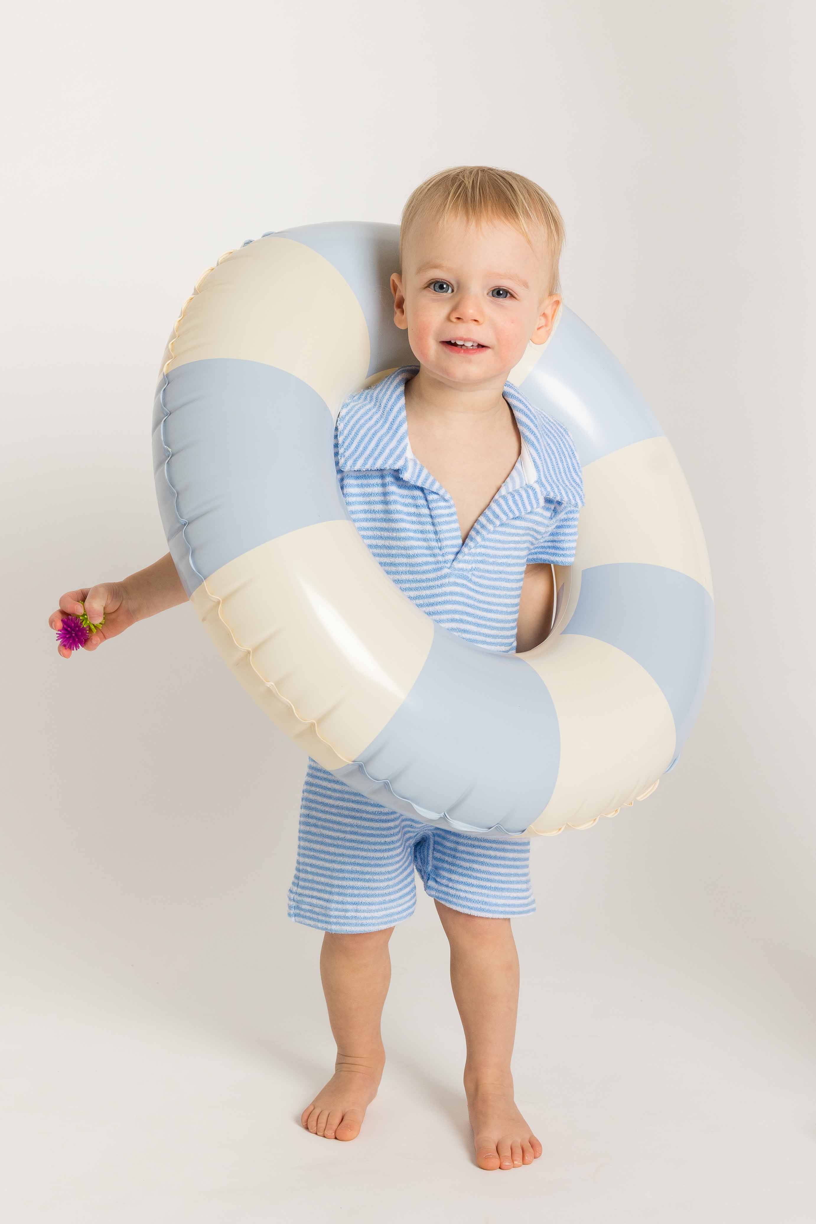 Child holding a striped inflatable ring on a white background