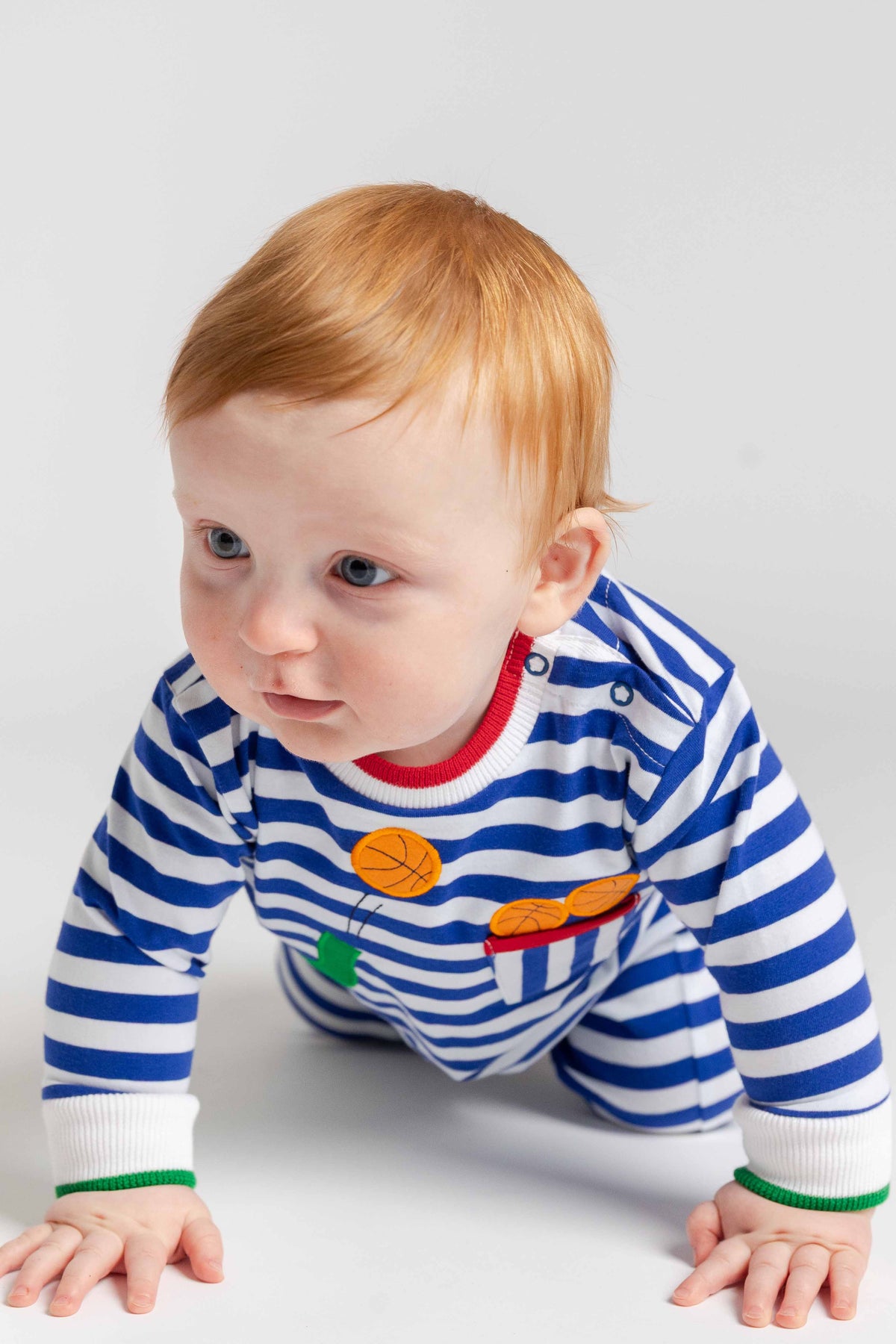 Baby wearing a blue and white striped shirt with colorful patches on a light gray background